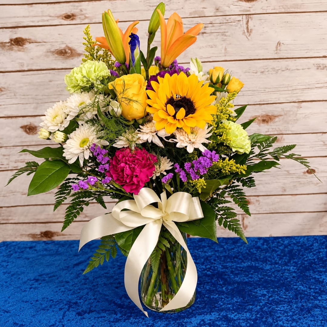 Mixed bouquet in a glass vase with a cream ribbon