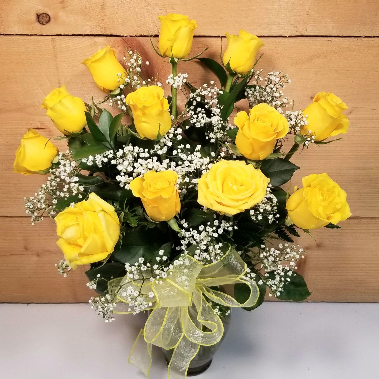 Bouquet of yellow roses with baby's breath in a glass vase
