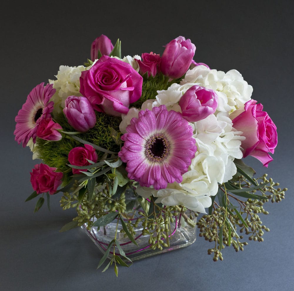 Pink roses and gerbera daisies arranged in a glass vase