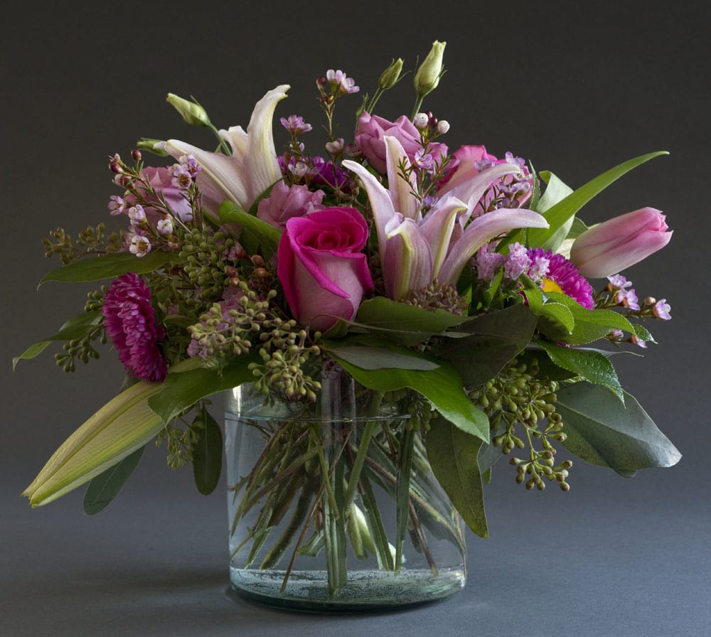 Pink lilies and roses arranged in a clear glass vase