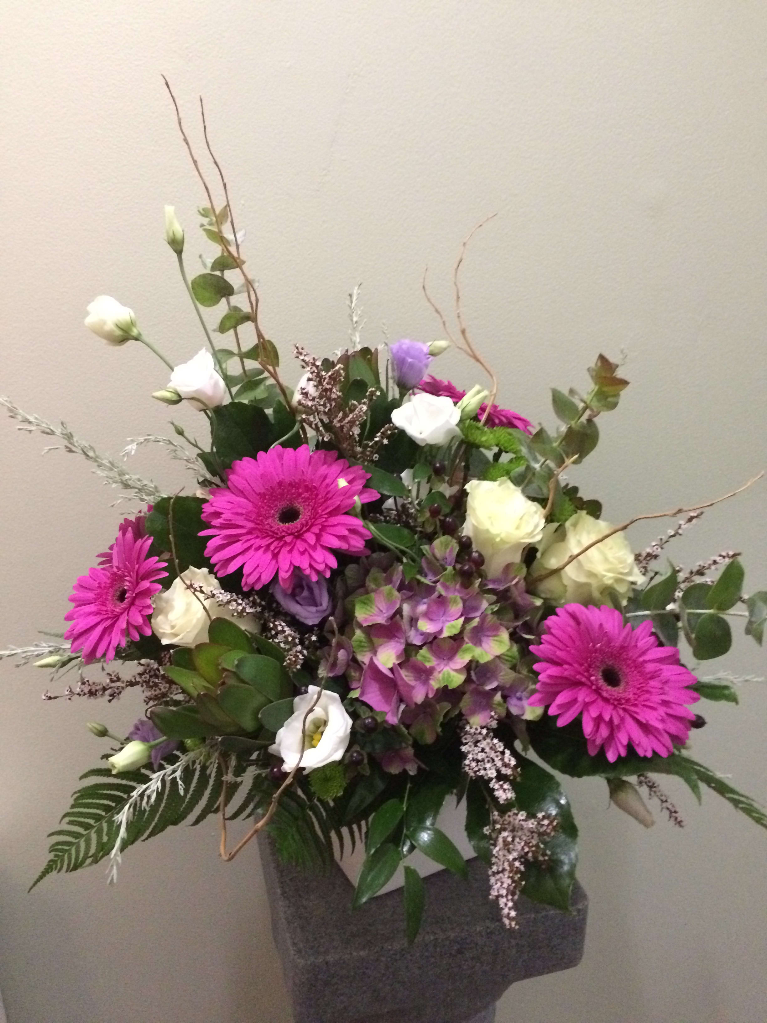 Mixed bouquet with bright pink daisies and white blooms in a gray vase