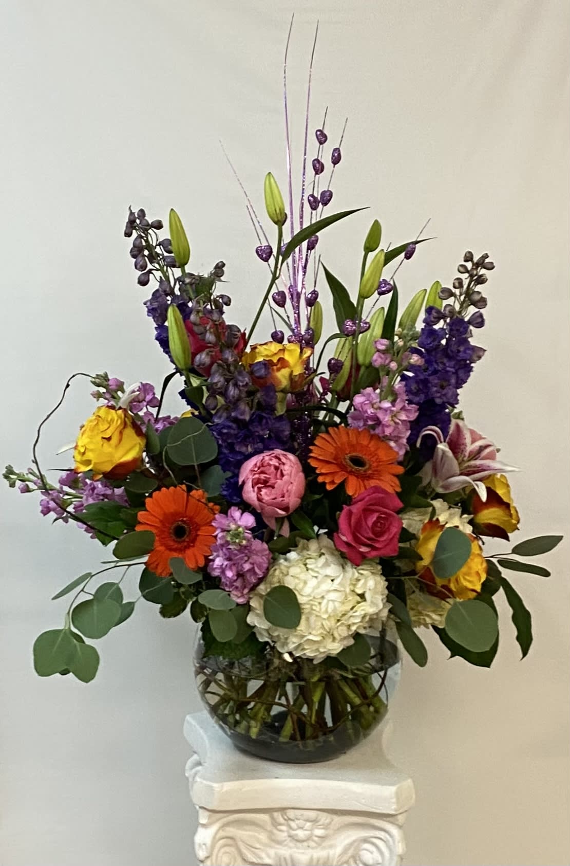 Colorful mixed bouquet in a glass vase with tall purple accents