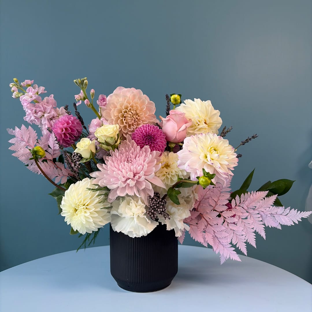 Pink and cream flower arrangement in a black vase