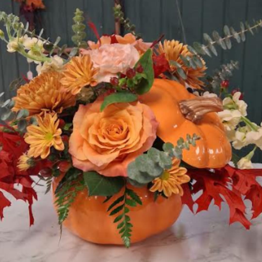 Orange pumpkin arrangement with peach roses and autumn flowers
