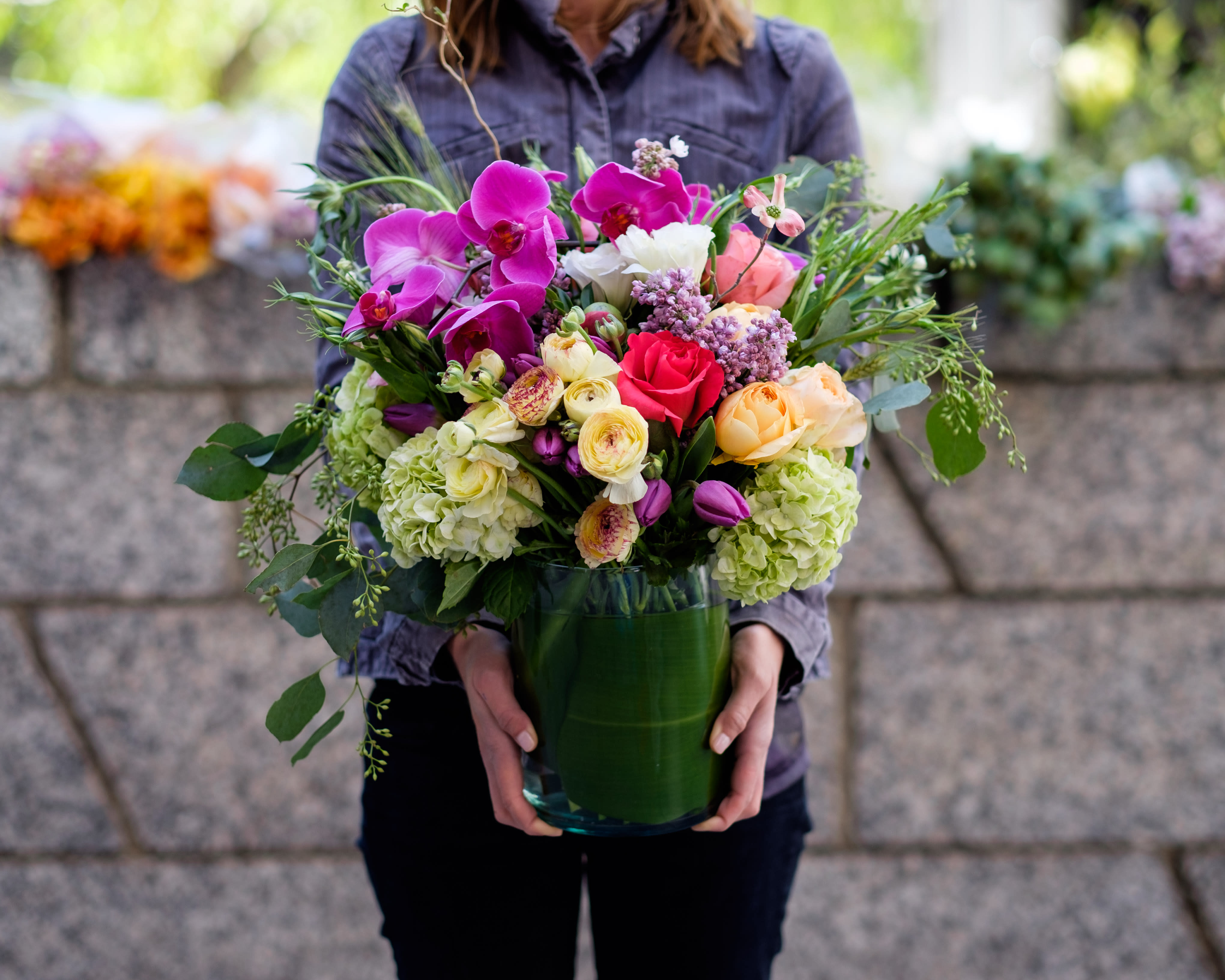 Mixed bouquet of orchids, roses, and hydrangeas in a glass vase