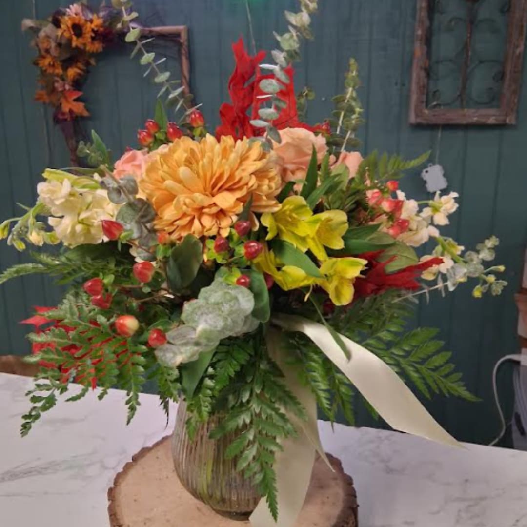 Mixed floral arrangement in a ribbed vase with a cream ribbon