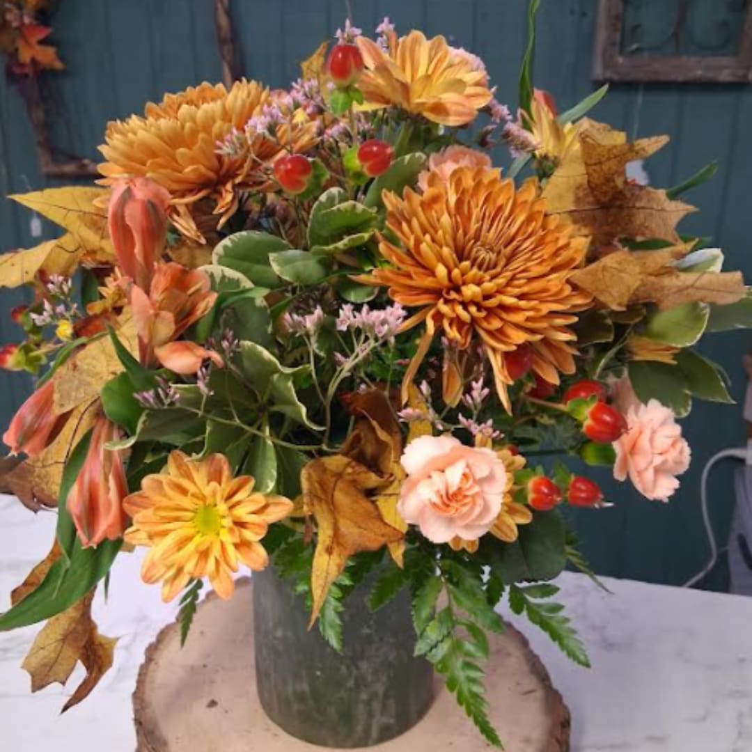 Autumn bouquet of orange chrysanthemums and peach carnations in a metal vase
