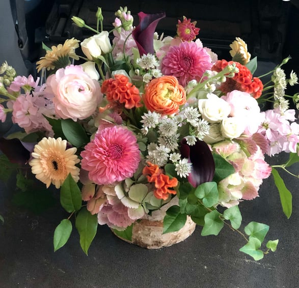Mixed bouquet in a birch container with pink, white, orange, and purple flowers
