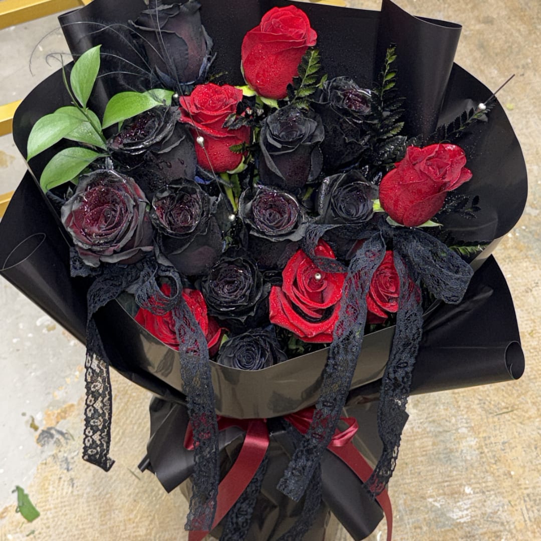 Bouquet of red and black roses wrapped in black paper with lace ribbons