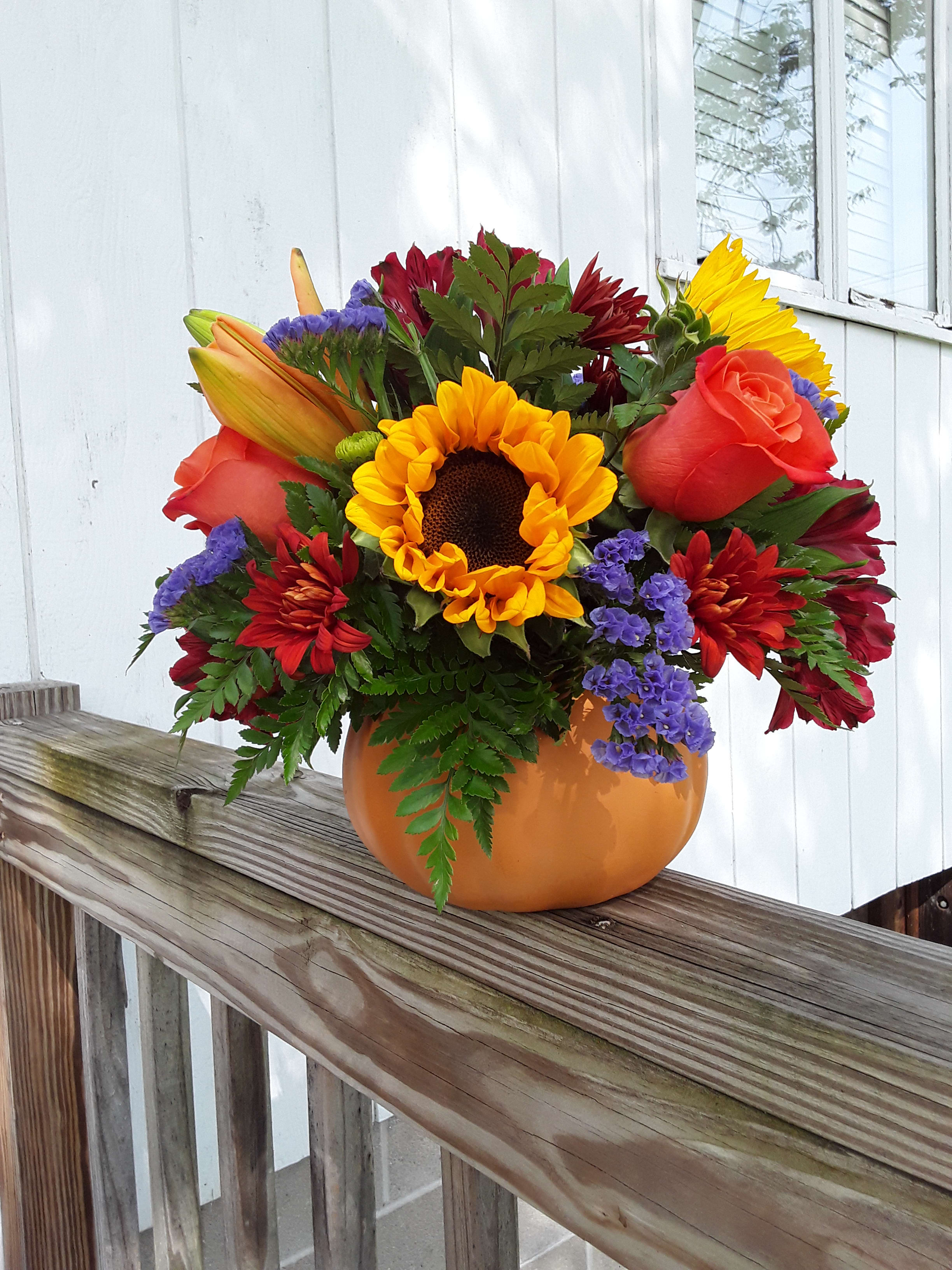 Fall Pumpkin Bouquet - Bright and cheerful fall sunflowers, orange roses, lilies, fall cushion poms and purple statice designed in a decorative pumpkin container.