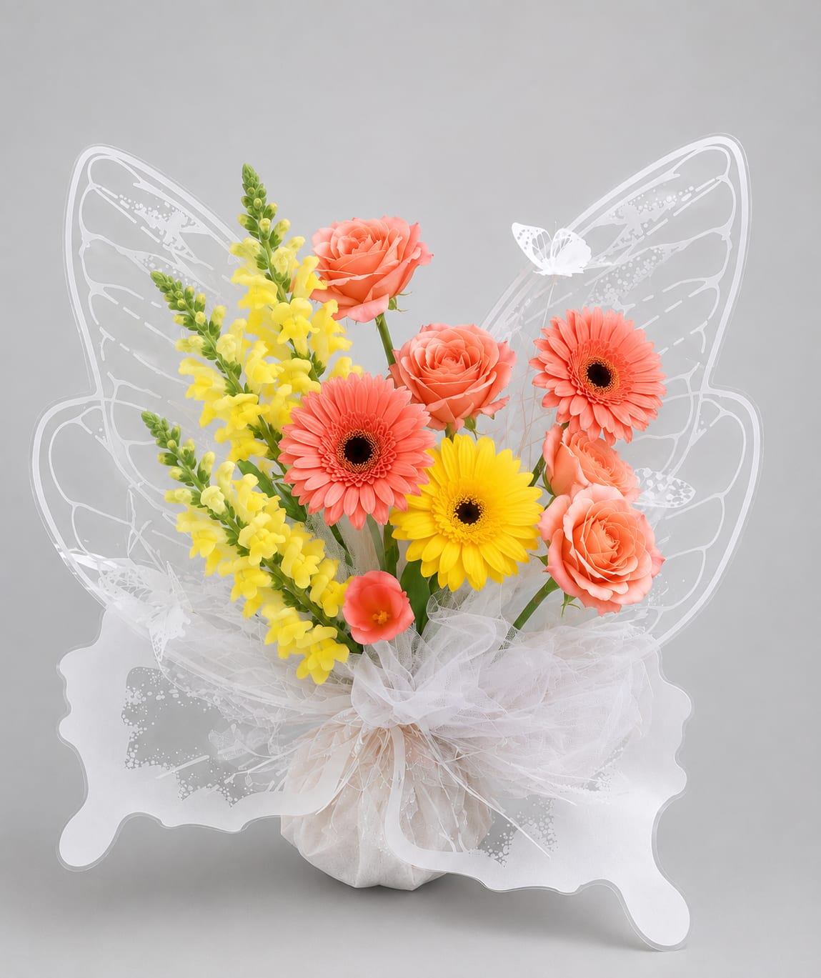 Butterfly-shaped bouquet with coral roses, gerbera daisies, and yellow snapdragons