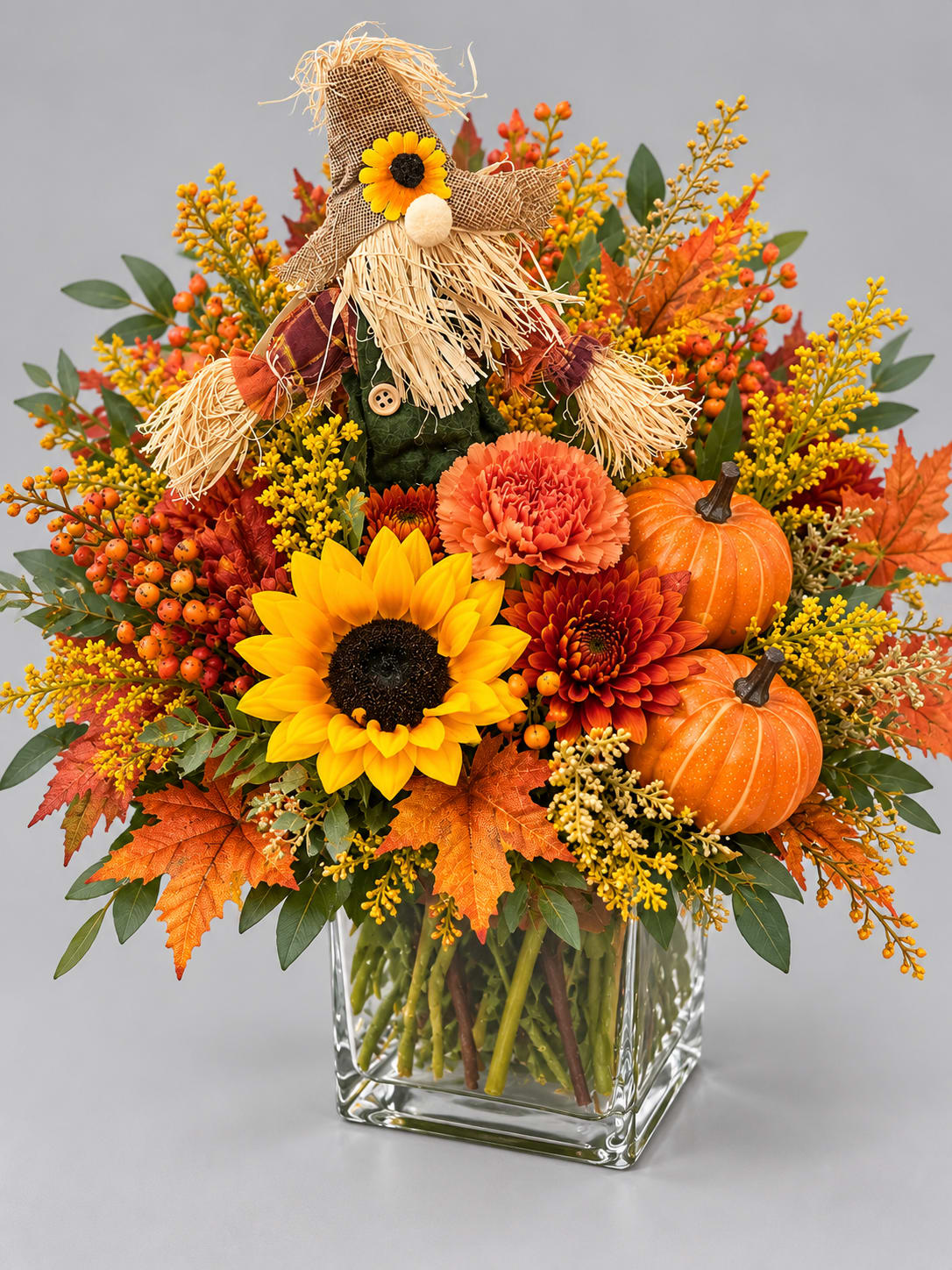 Fall bouquet with sunflowers, mums, pumpkins, and a scarecrow in a glass vase
