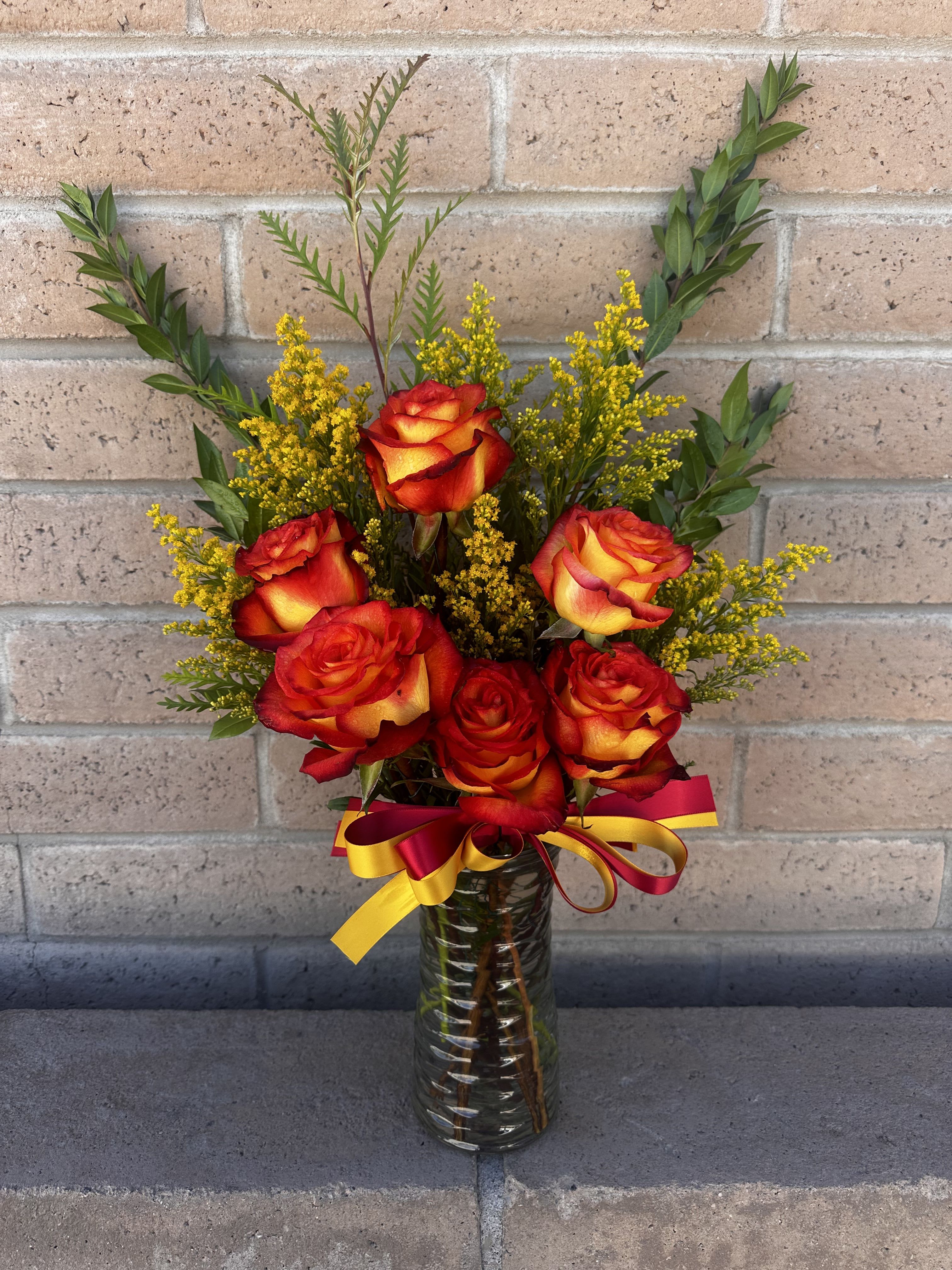 Bouquet of red and yellow roses in a glass vase with a ribbon