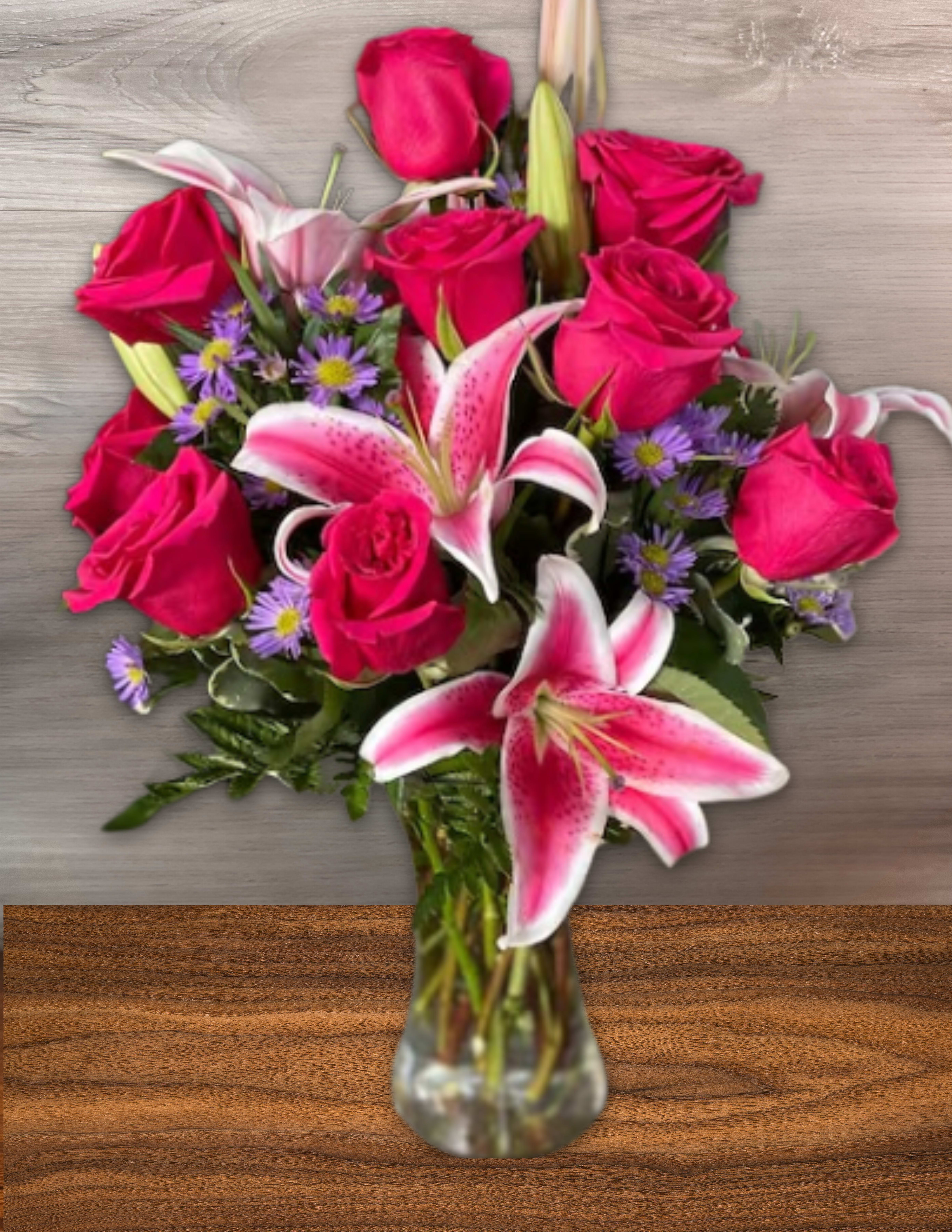 Pink roses and lilies arranged in a clear glass vase