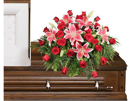 Red roses and pink lilies arranged on a wooden casket