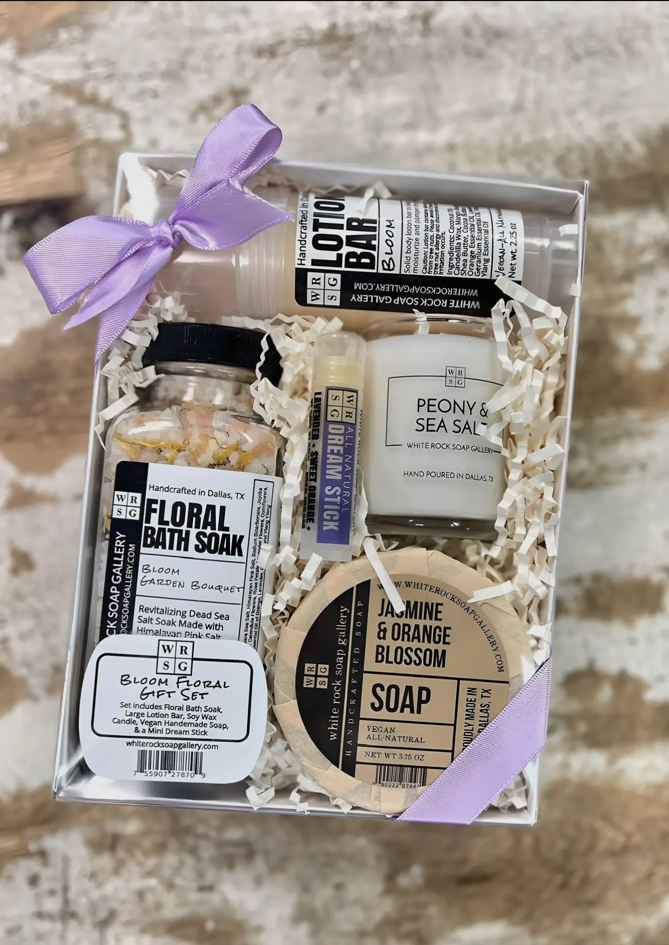 Gift box with floral-scented bath and soap items tied with lavender ribbon