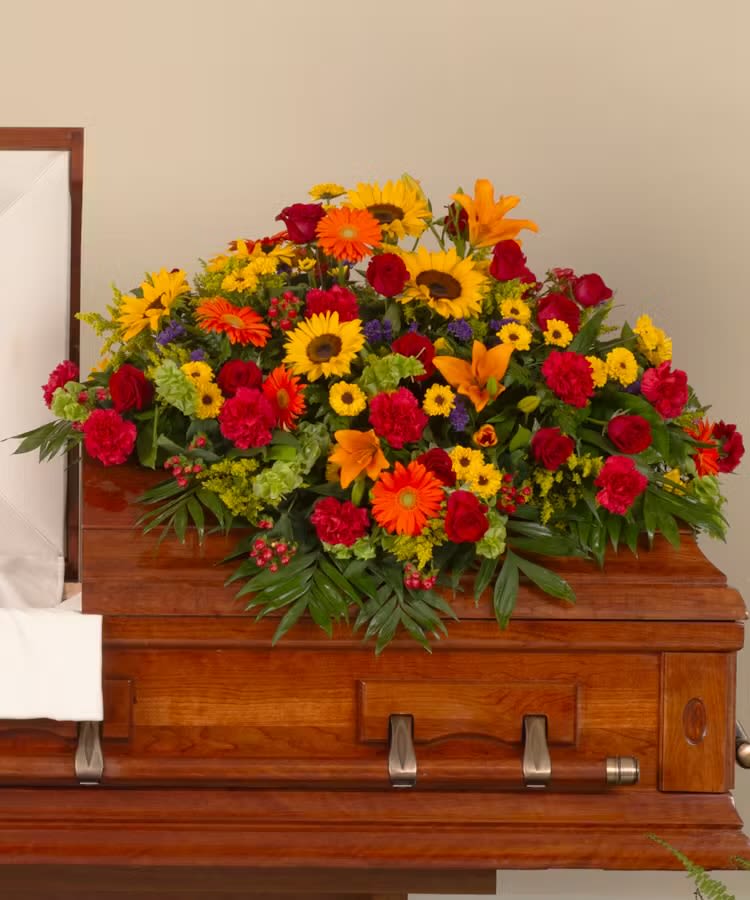 Bright mixed flower spray on a wooden casket