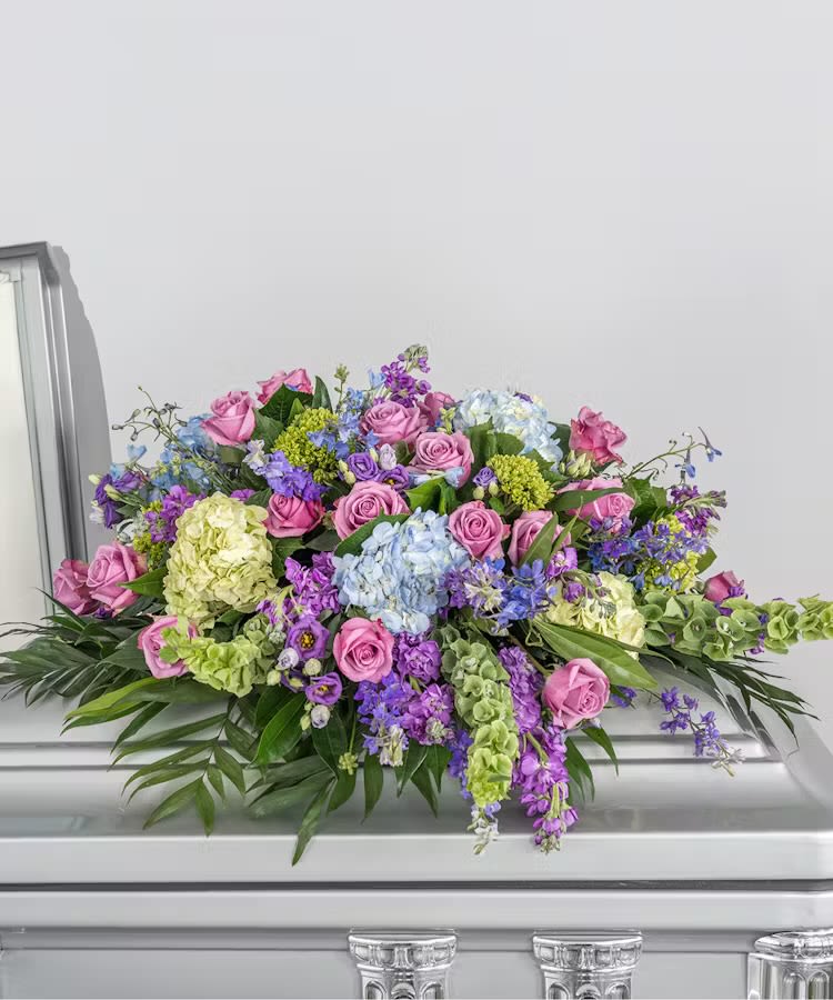 Large floral casket spray with pink roses and purple blooms