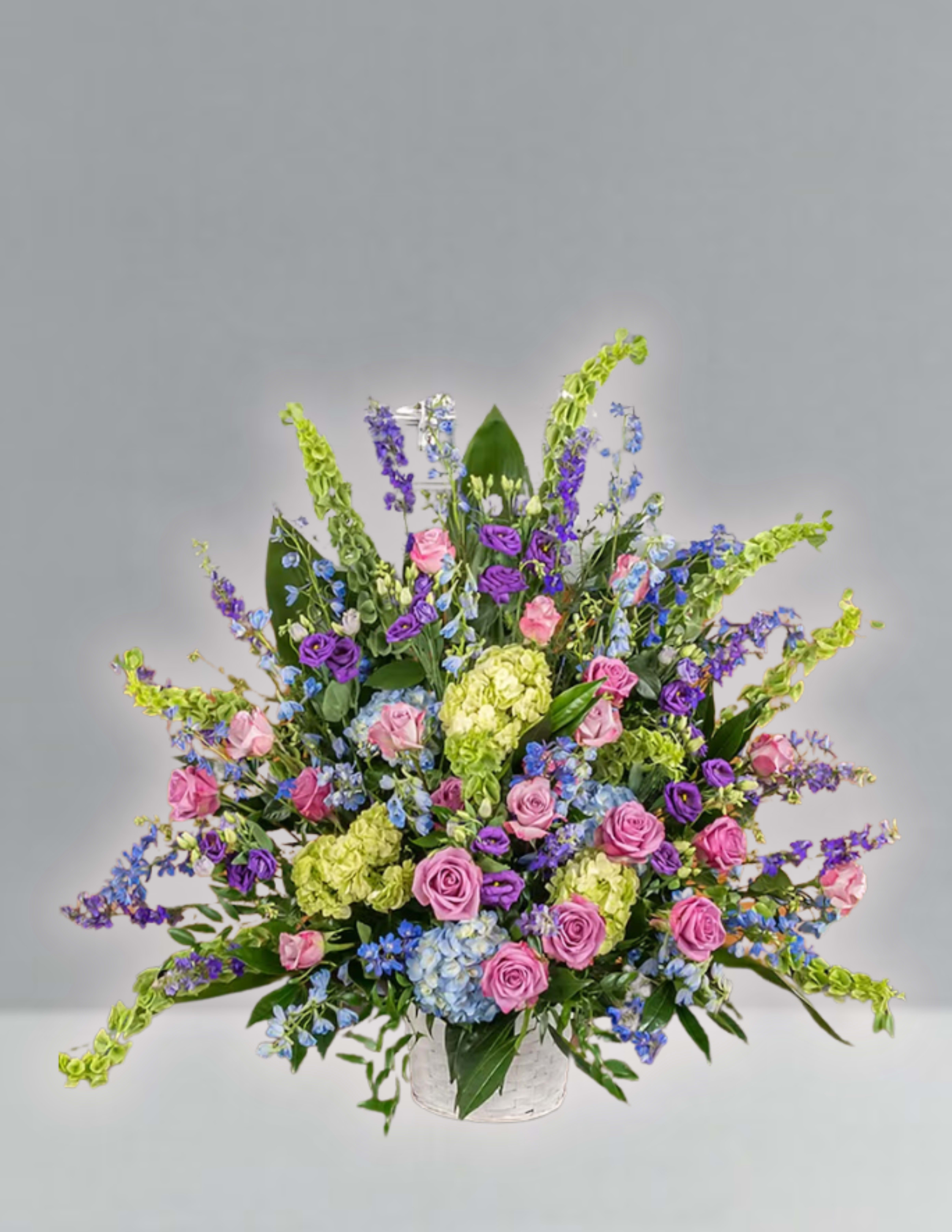 Large mixed bouquet of pink, purple, blue, and green flowers in a clear vase
