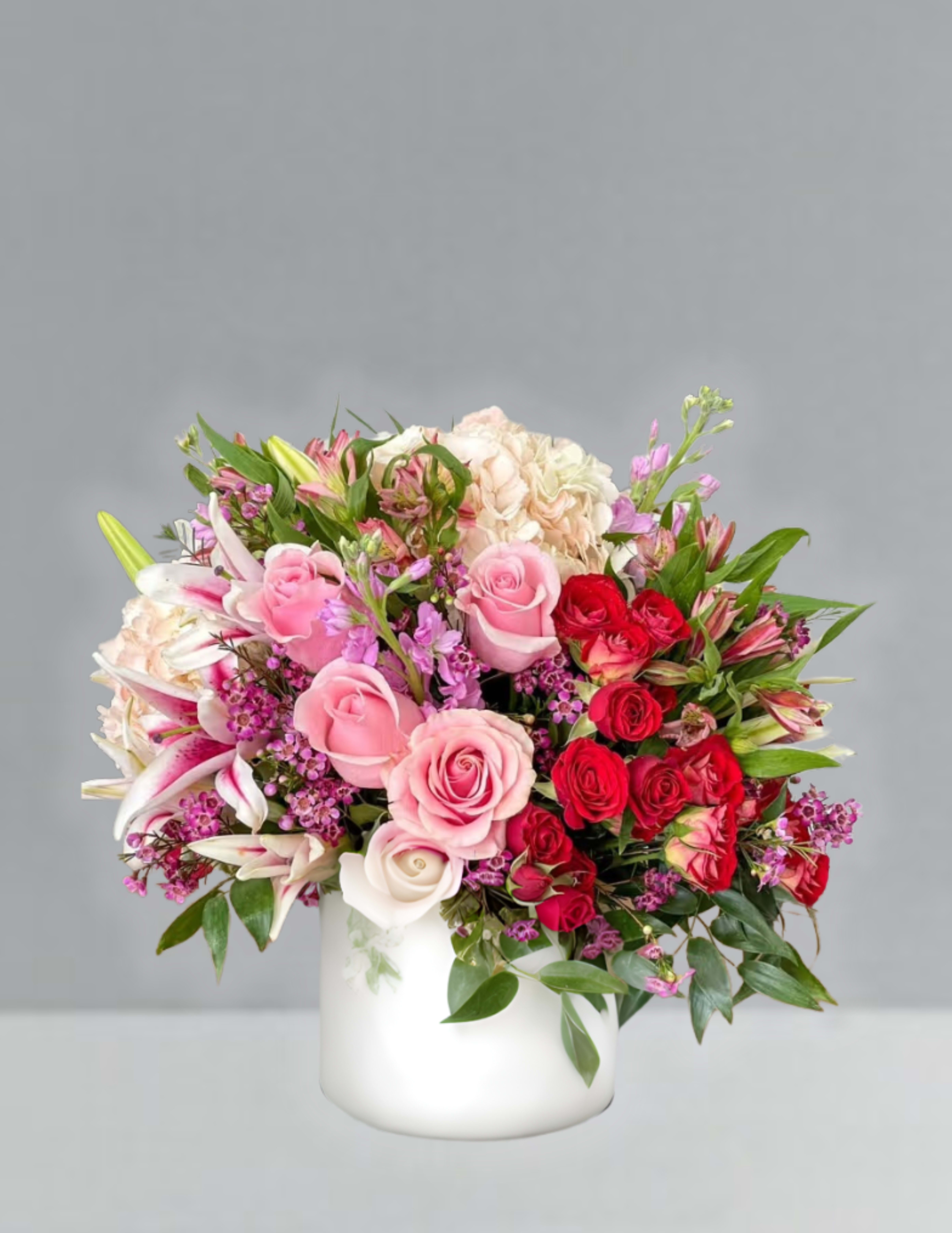 Mixed pink and red flower arrangement in a white vase