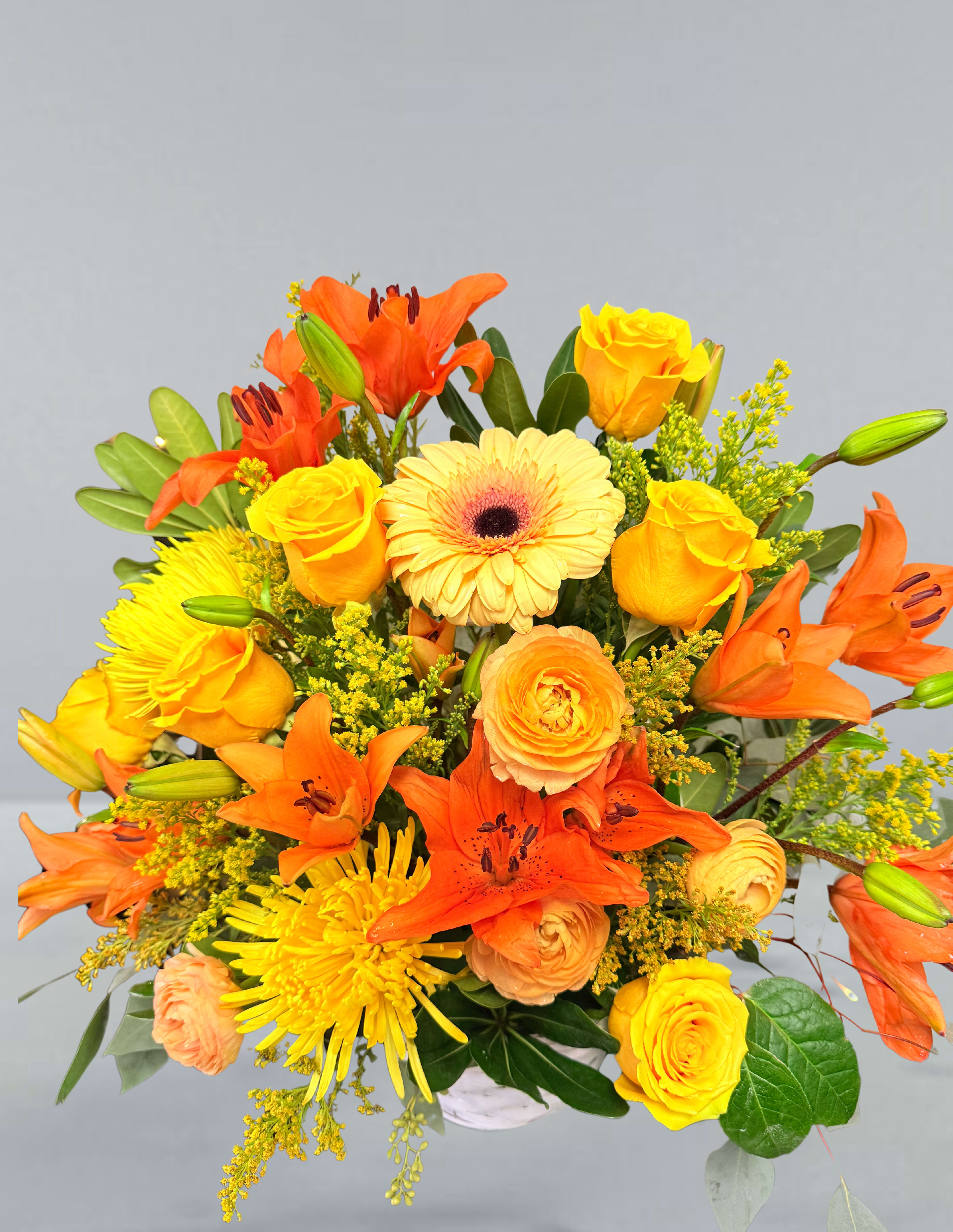 Sunrise serenity  - Lift spirits spirits with this bold and bright basket arrangement including yellow roses, orange lily's, yellow chrysanthemums, peach ranunculus, and solidago.
