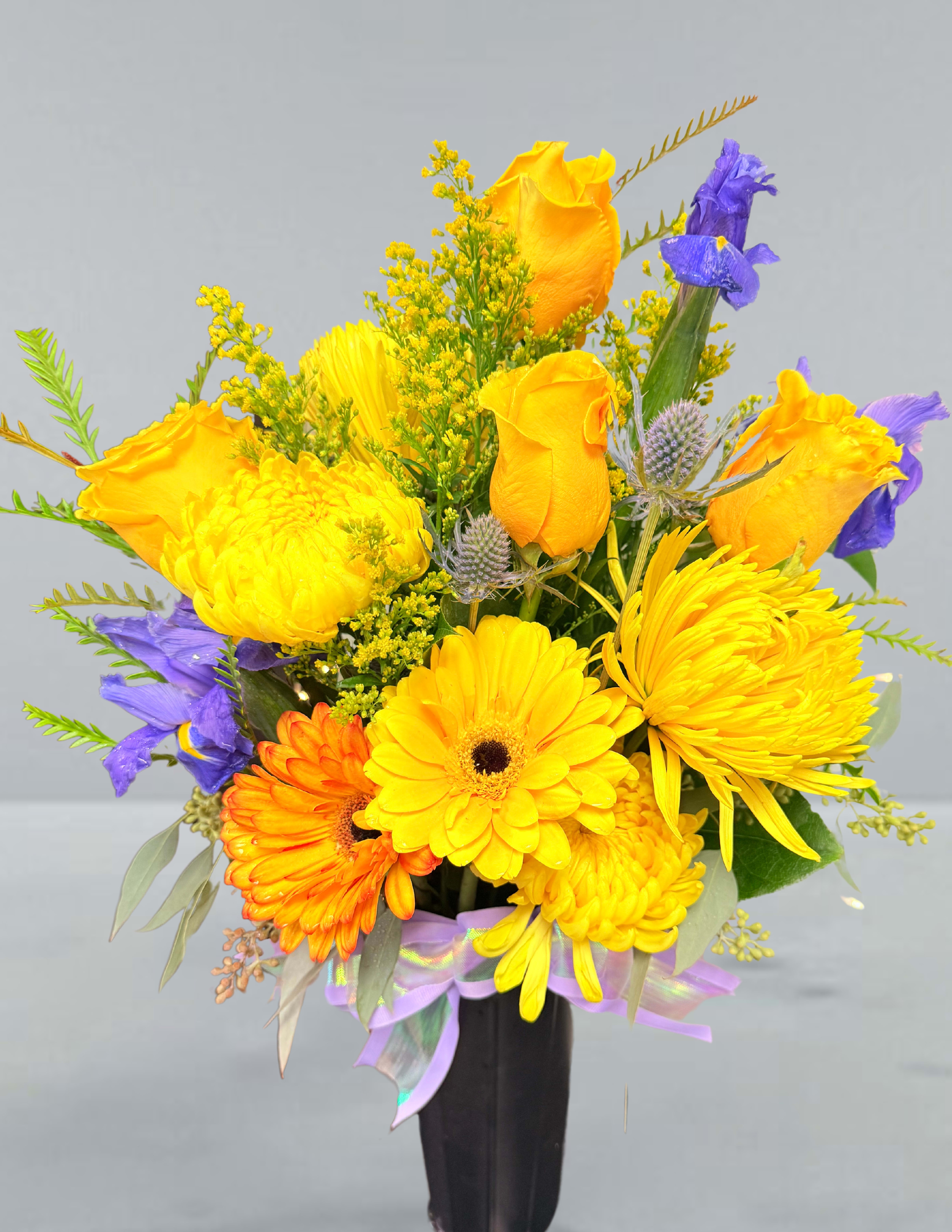 Bright yellow and purple mixed bouquet in a black vase