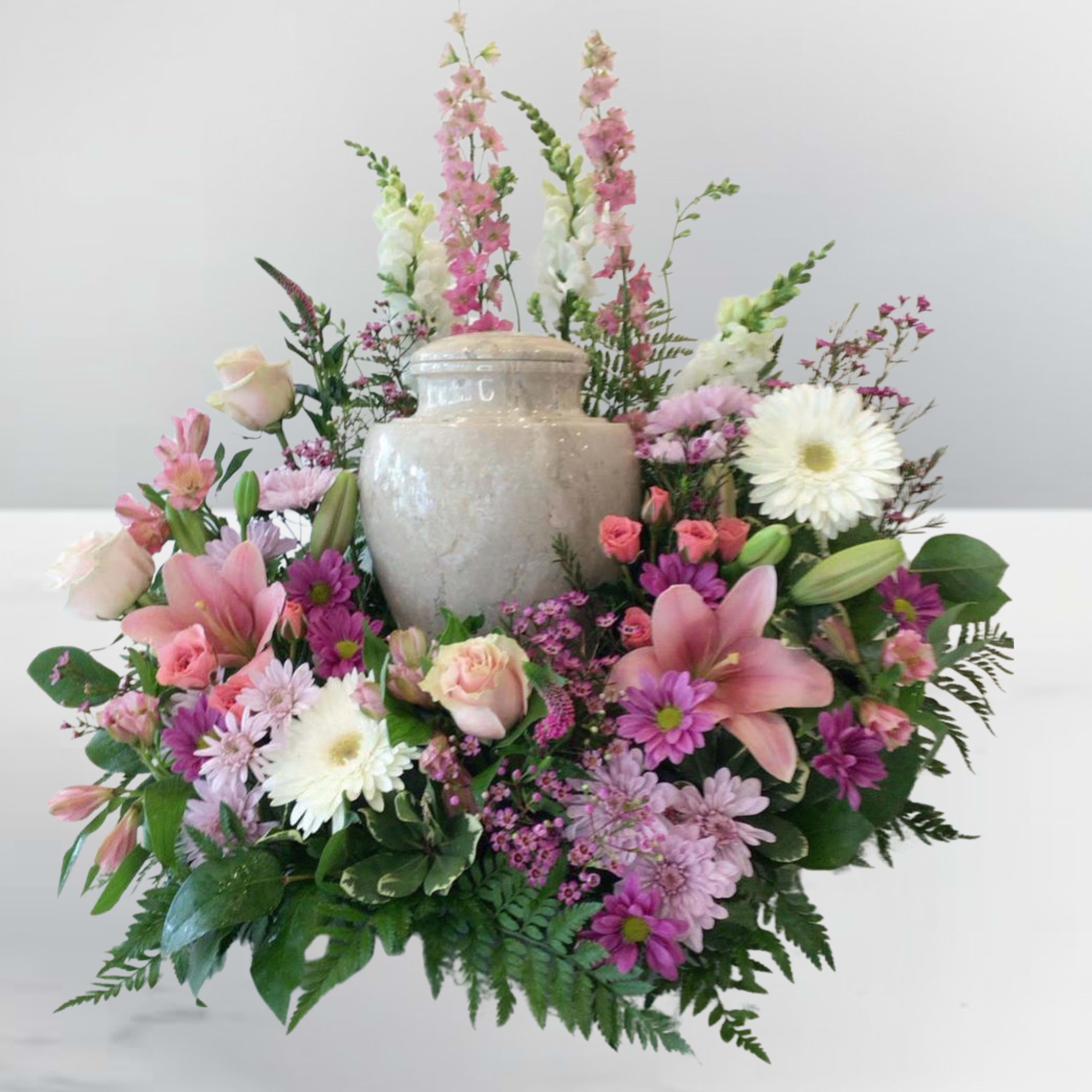 Pink and white mixed flower arrangement around a beige urn