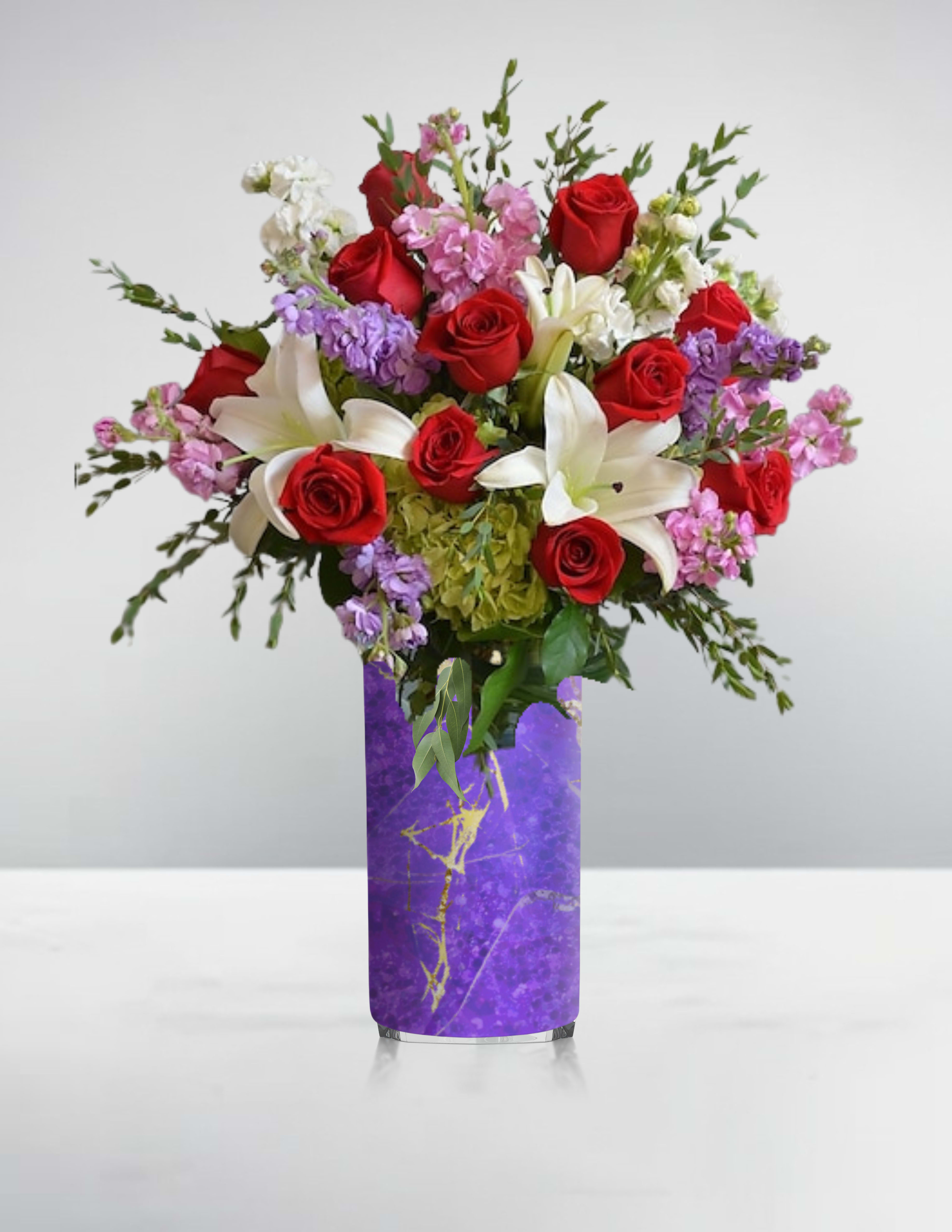Bouquet of red roses, white lilies, and pink flowers in a purple vase