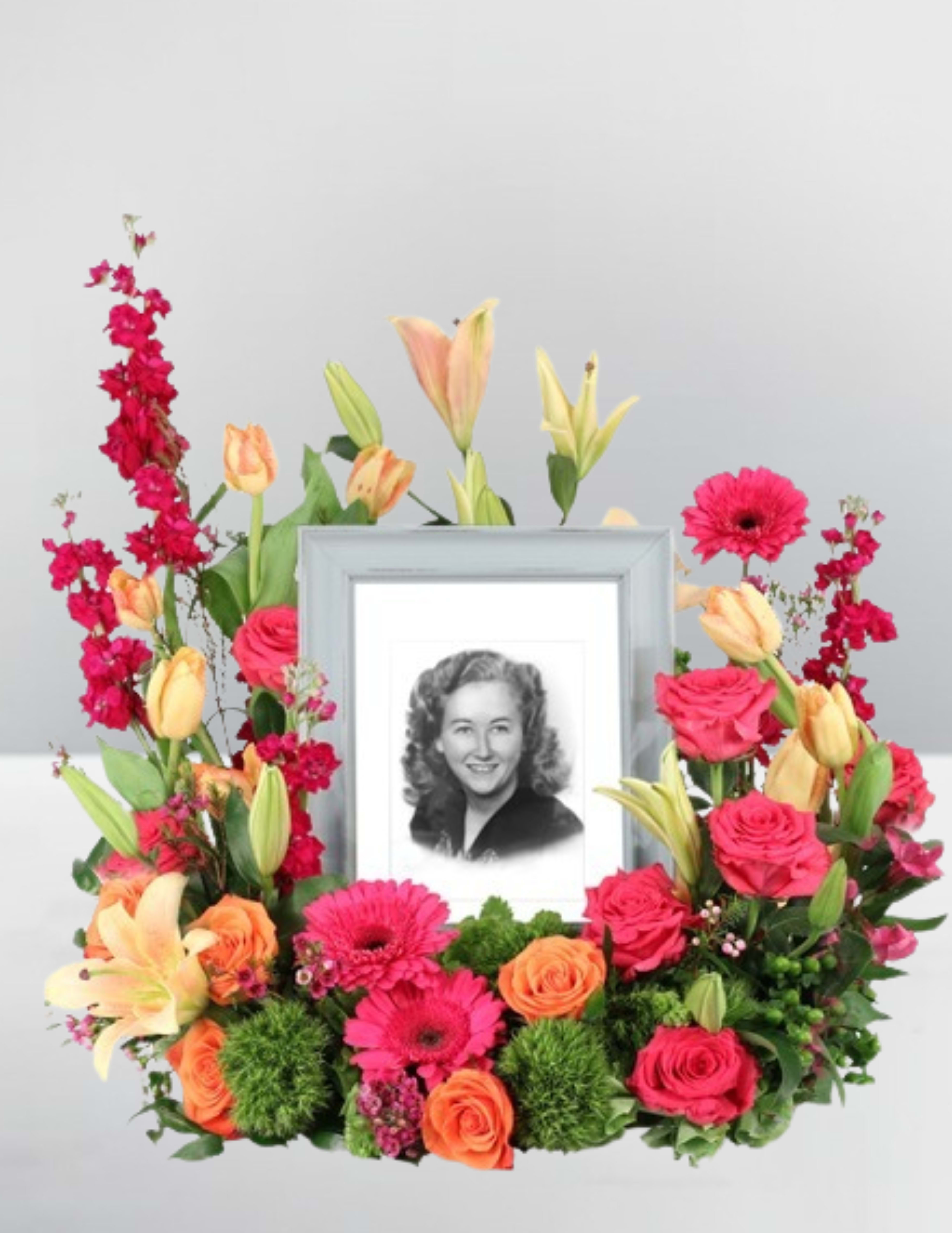Framed black-and-white portrait surrounded by pink, orange, and yellow flowers