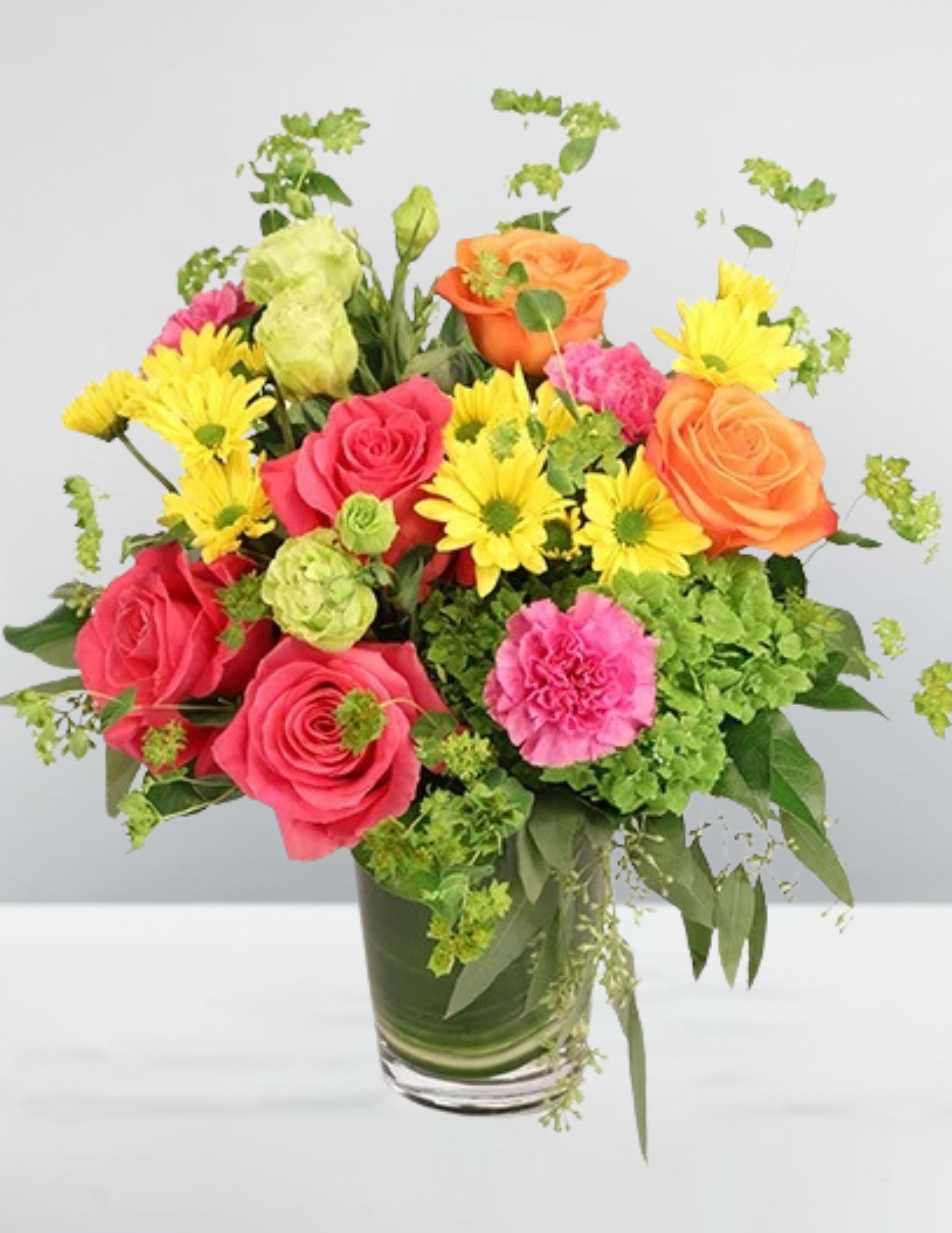 Mixed bouquet of roses, daisies, and carnations in a glass vase