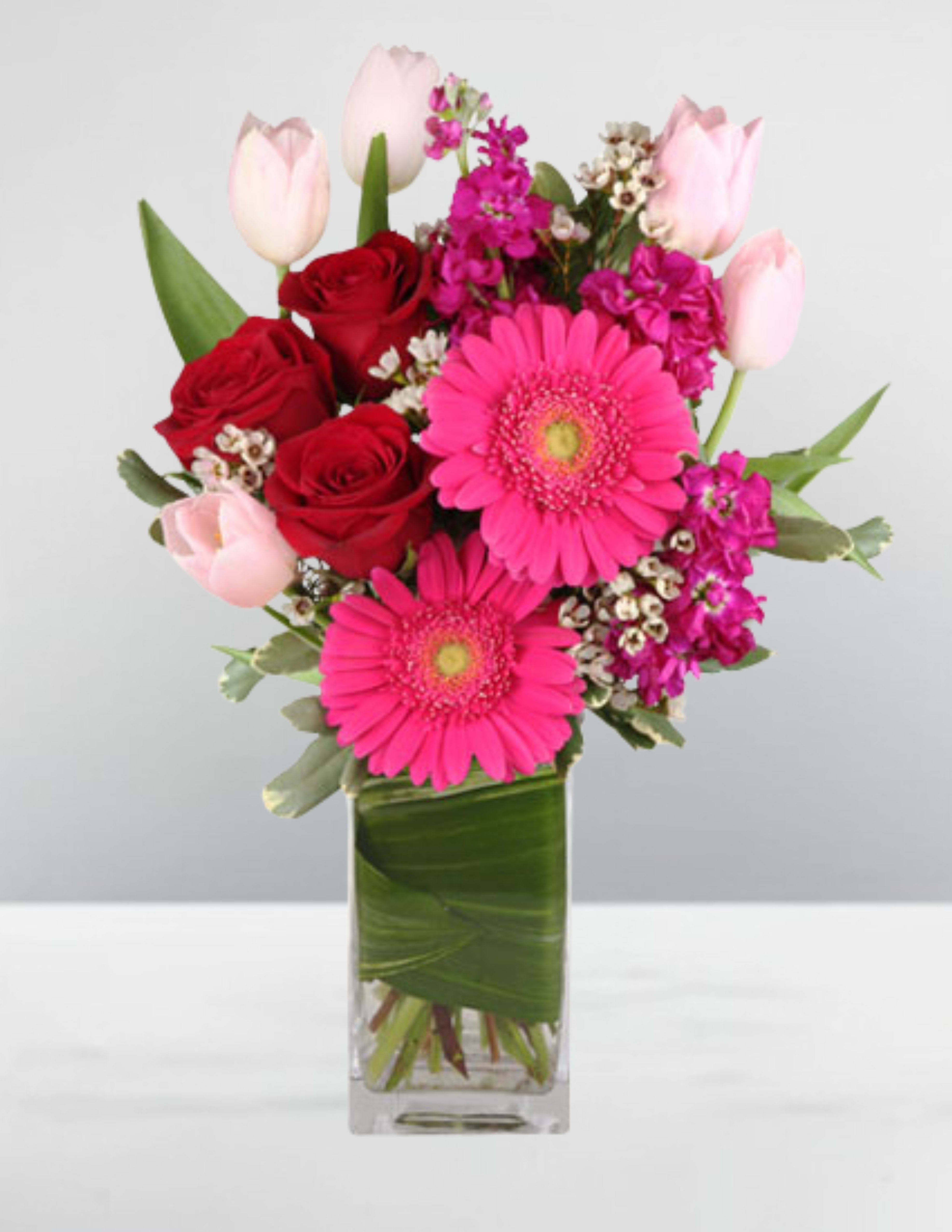 Pink and red mixed bouquet in a clear rectangular vase