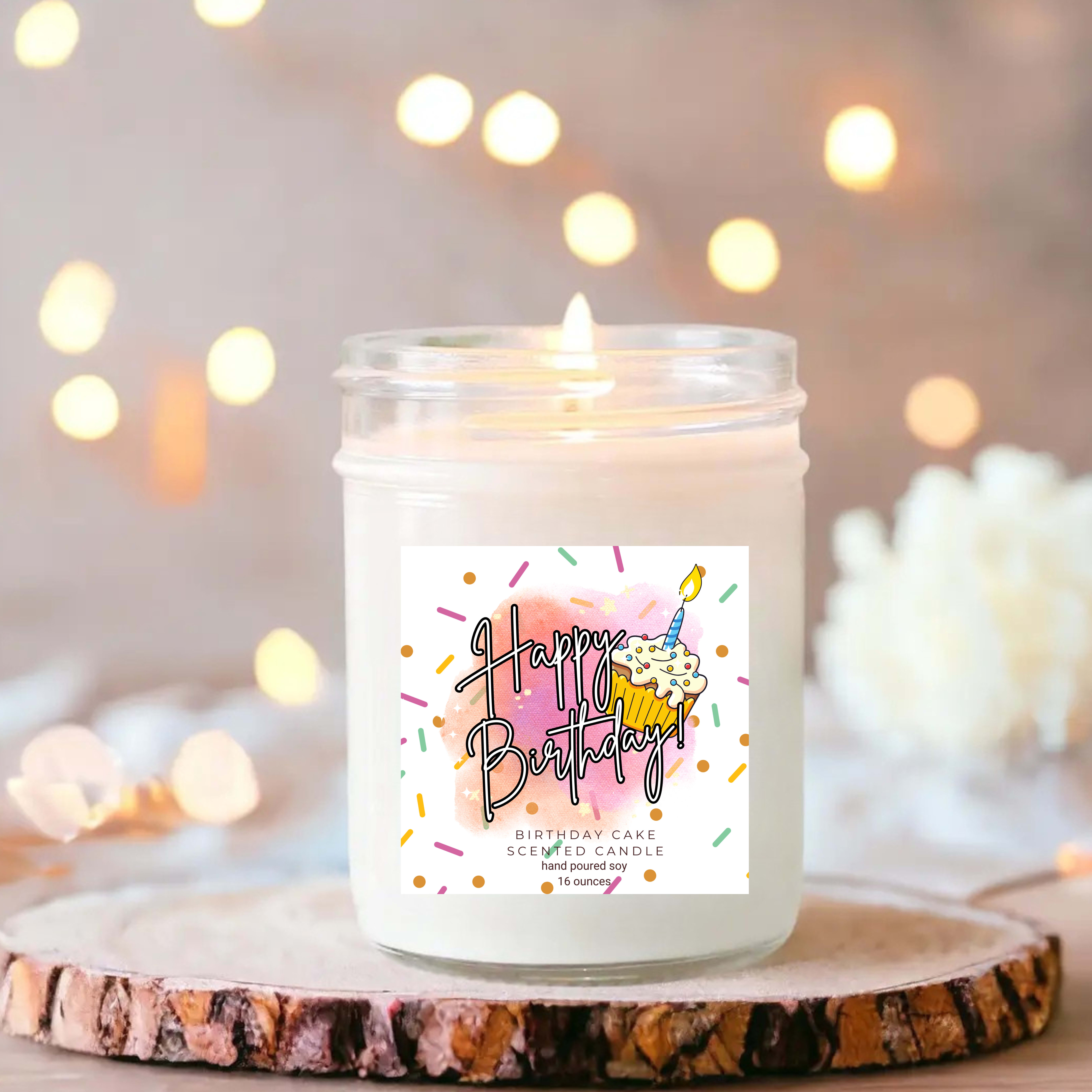 Birthday cake scented candle in a glass jar with a lit wick