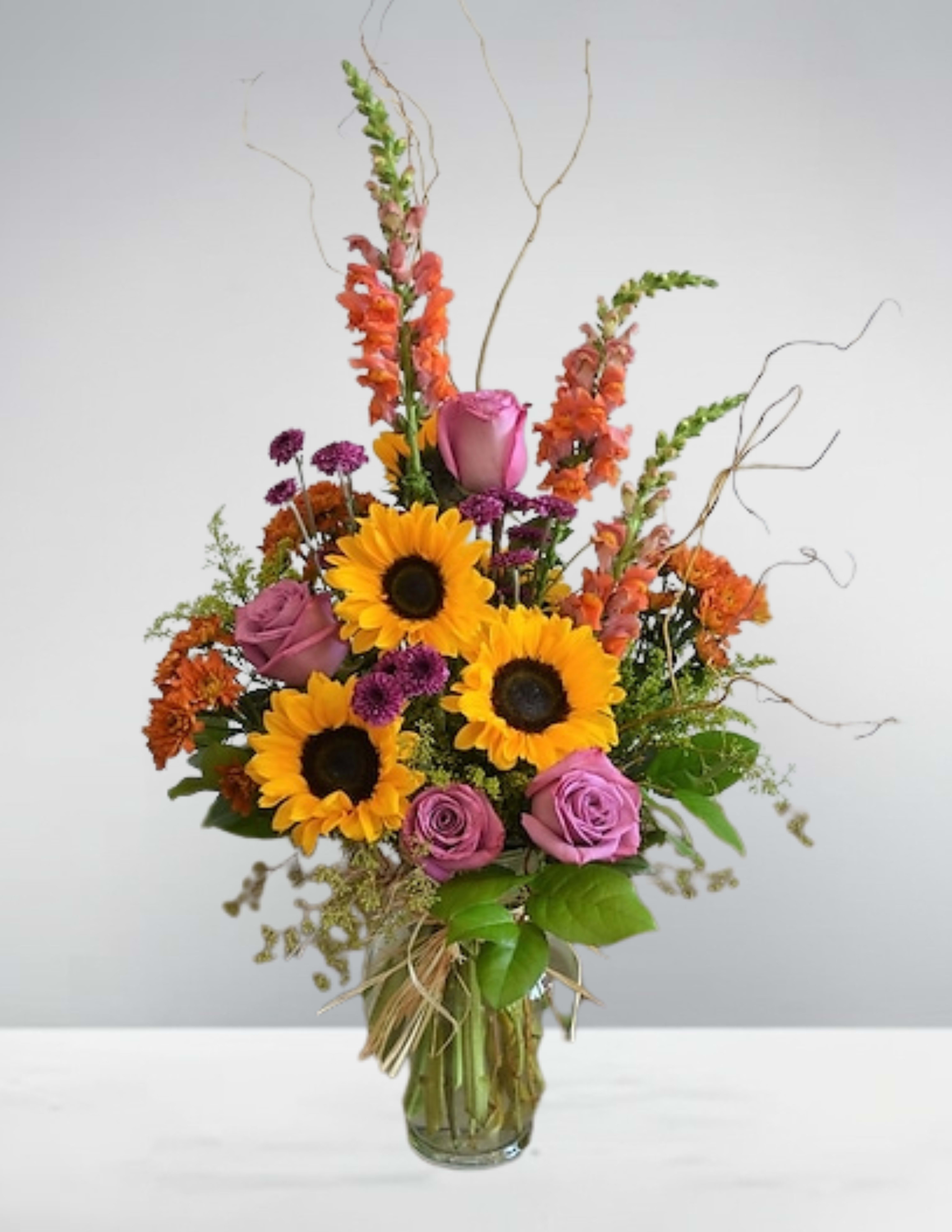 Sunflowers and purple roses in a glass vase