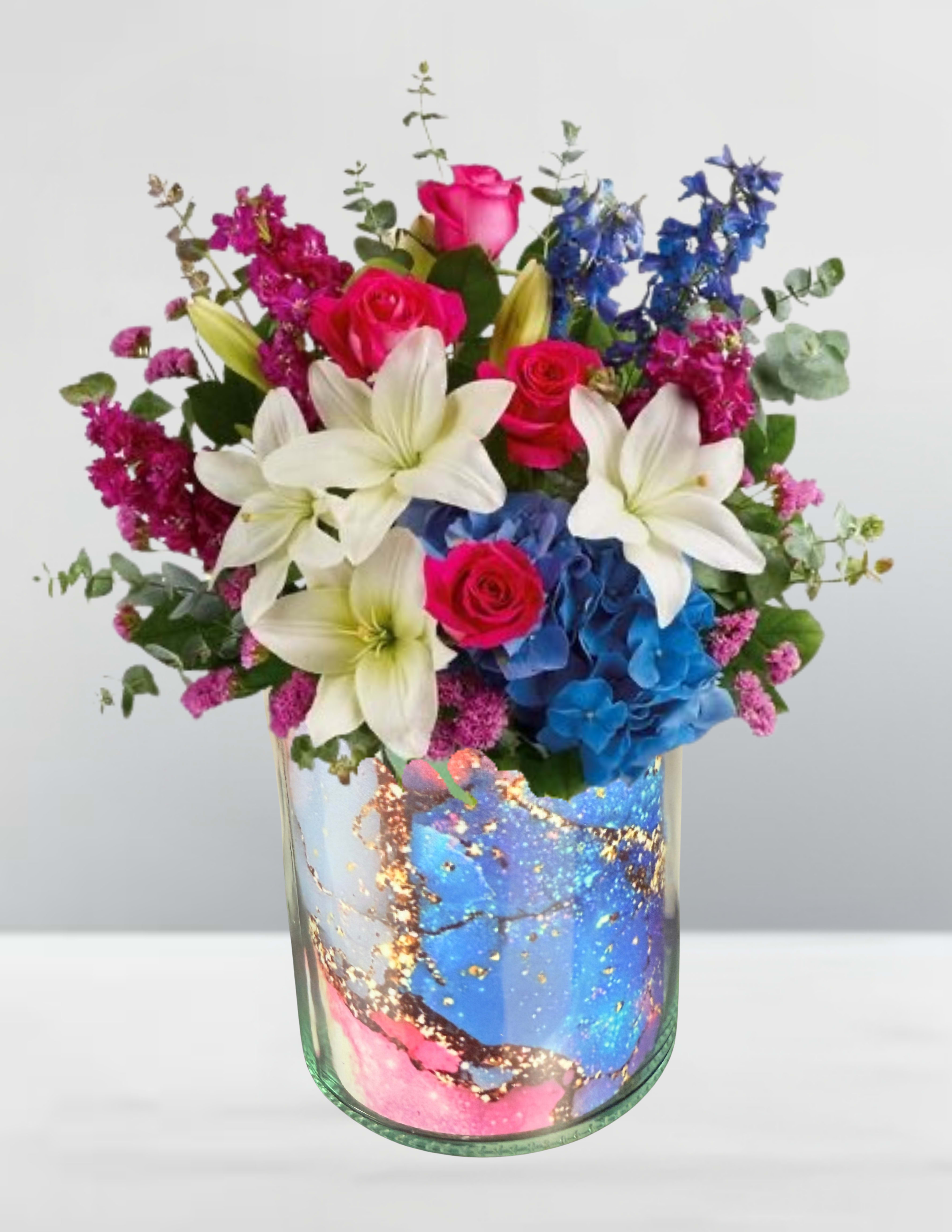 Bouquet of pink roses, white lilies, and blue hydrangeas in a glass vase
