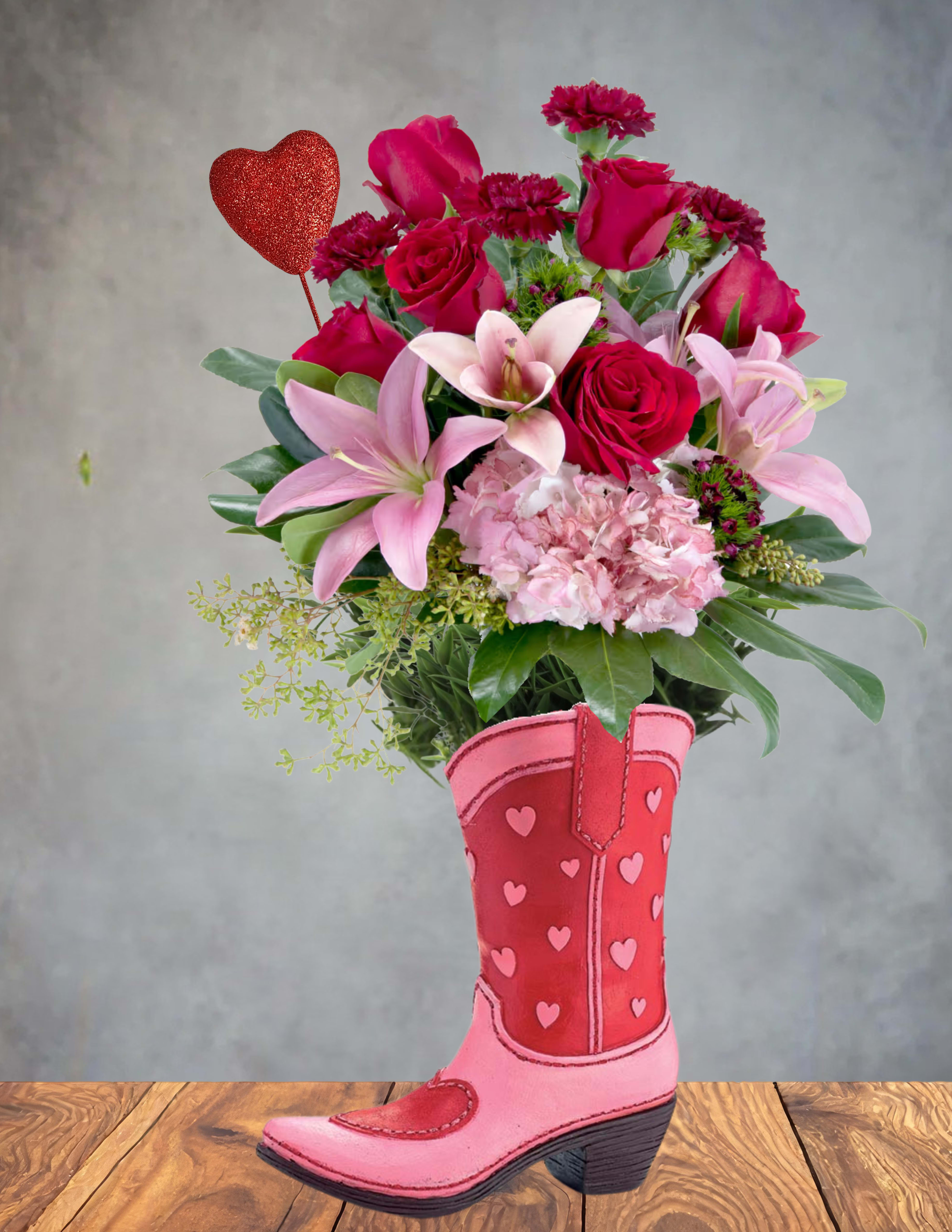 Pink and red flower arrangement in a heart-decorated cowboy boot vase