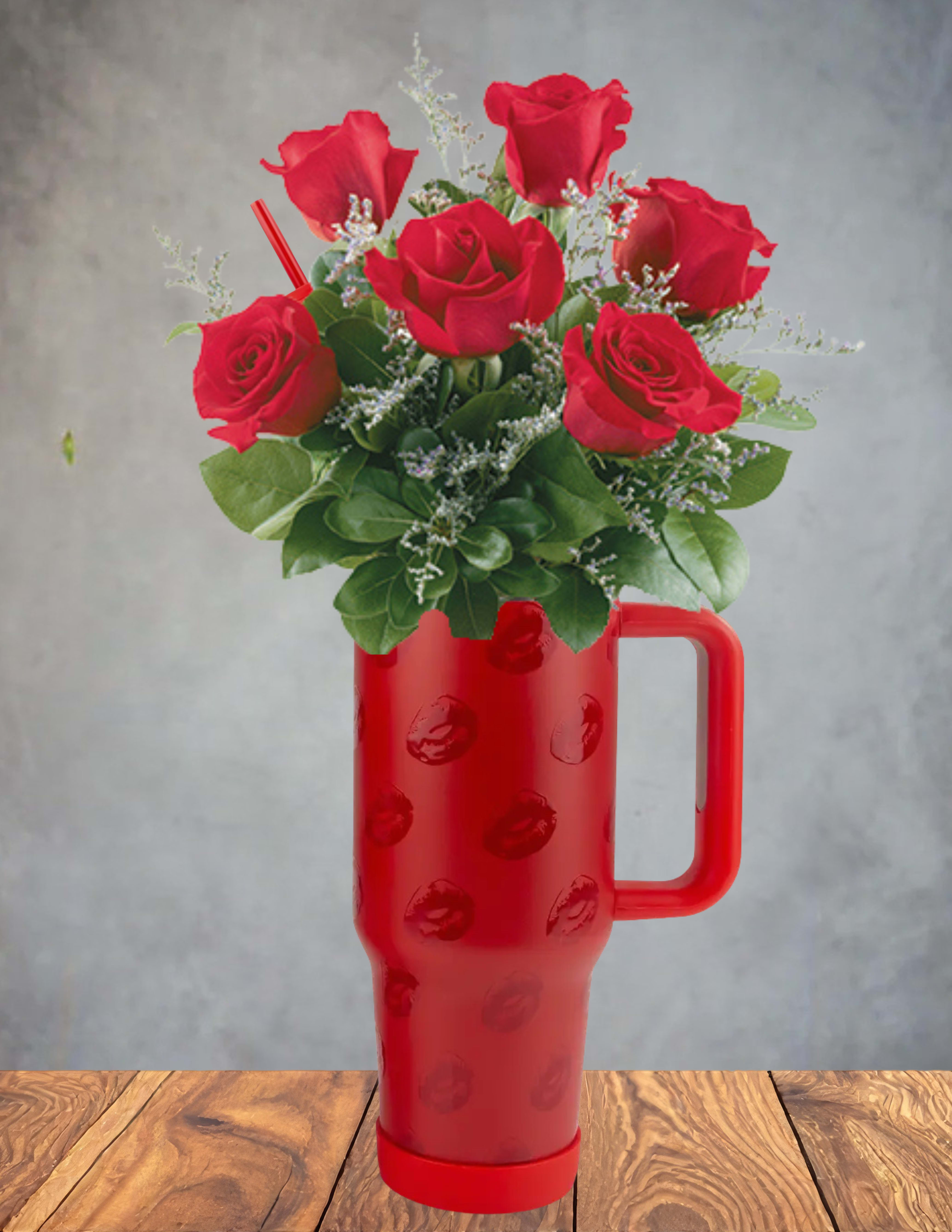 Red roses arranged in a red handled tumbler vase