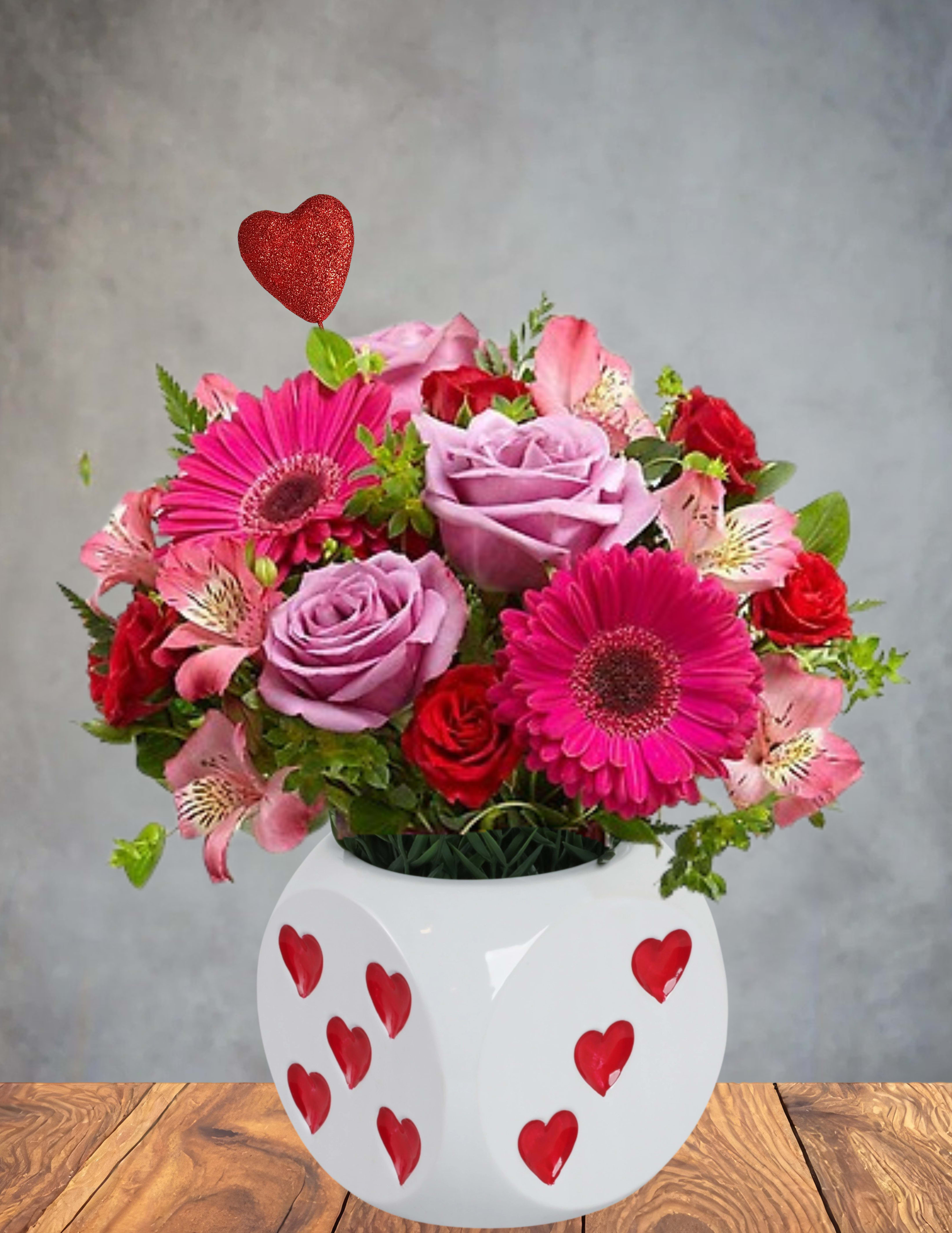 Pink and red flower arrangement in a white heart-decorated vase with a red heart pick