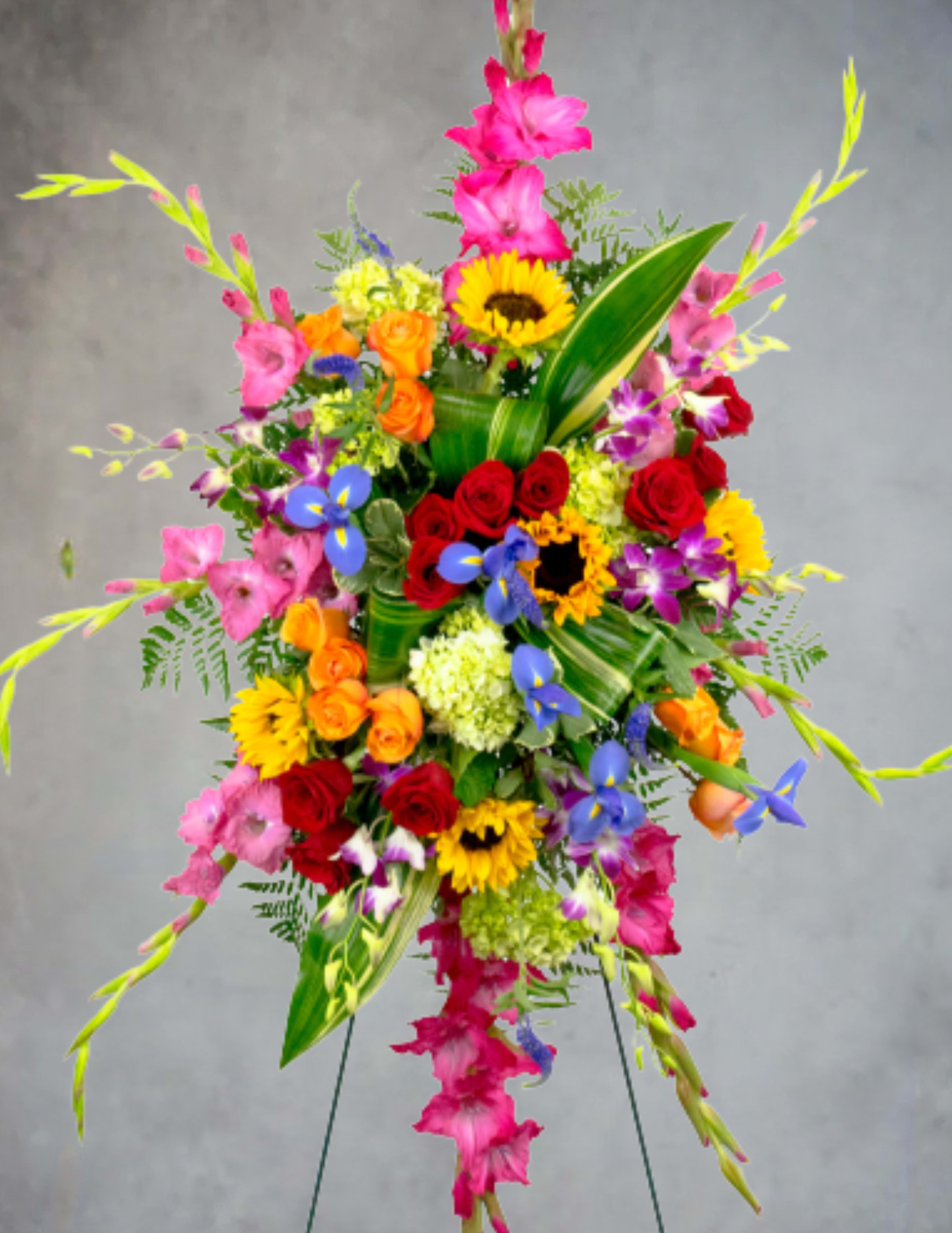 Tall colorful standing floral spray with roses, sunflowers, and orchids