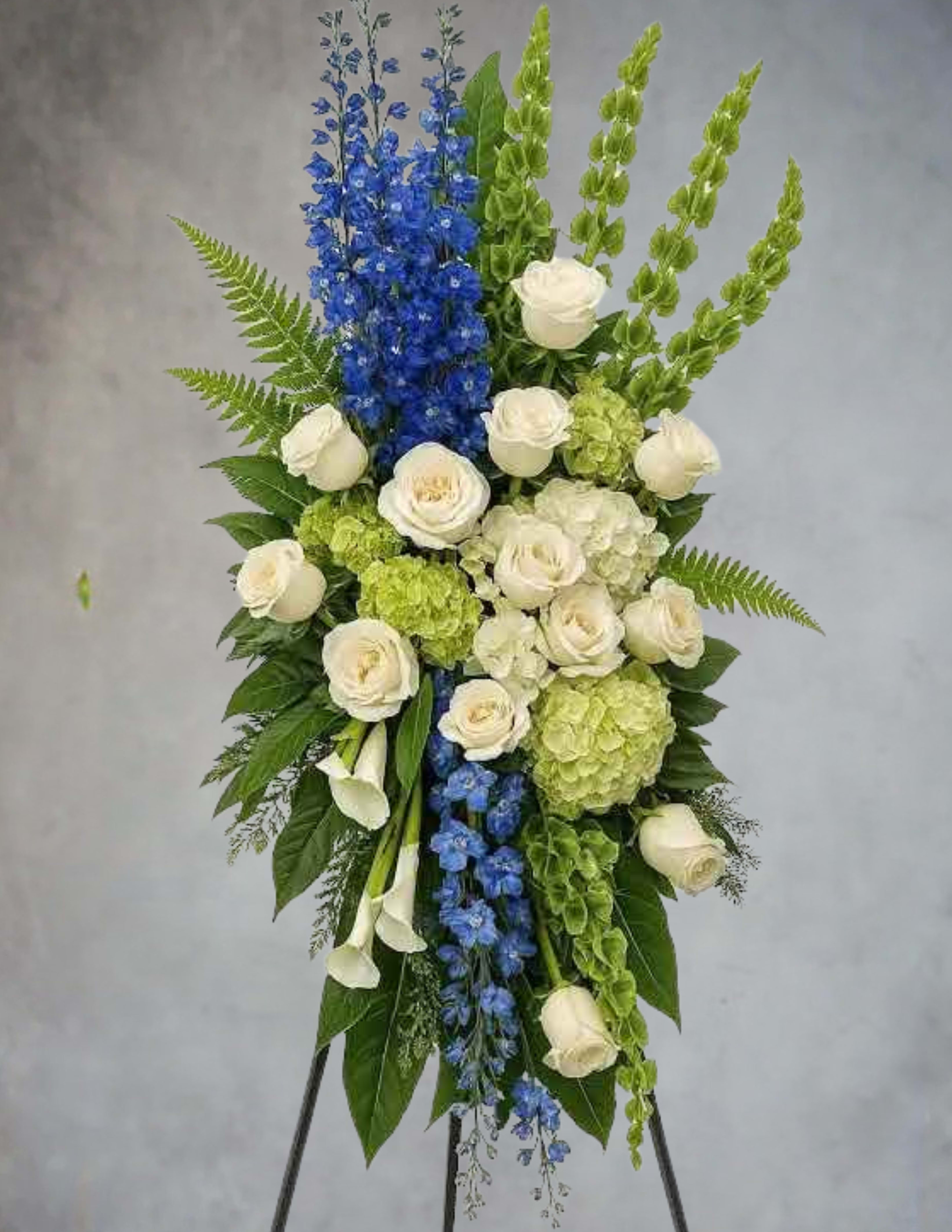 Standing floral spray with white roses, blue delphinium, and green hydrangea
