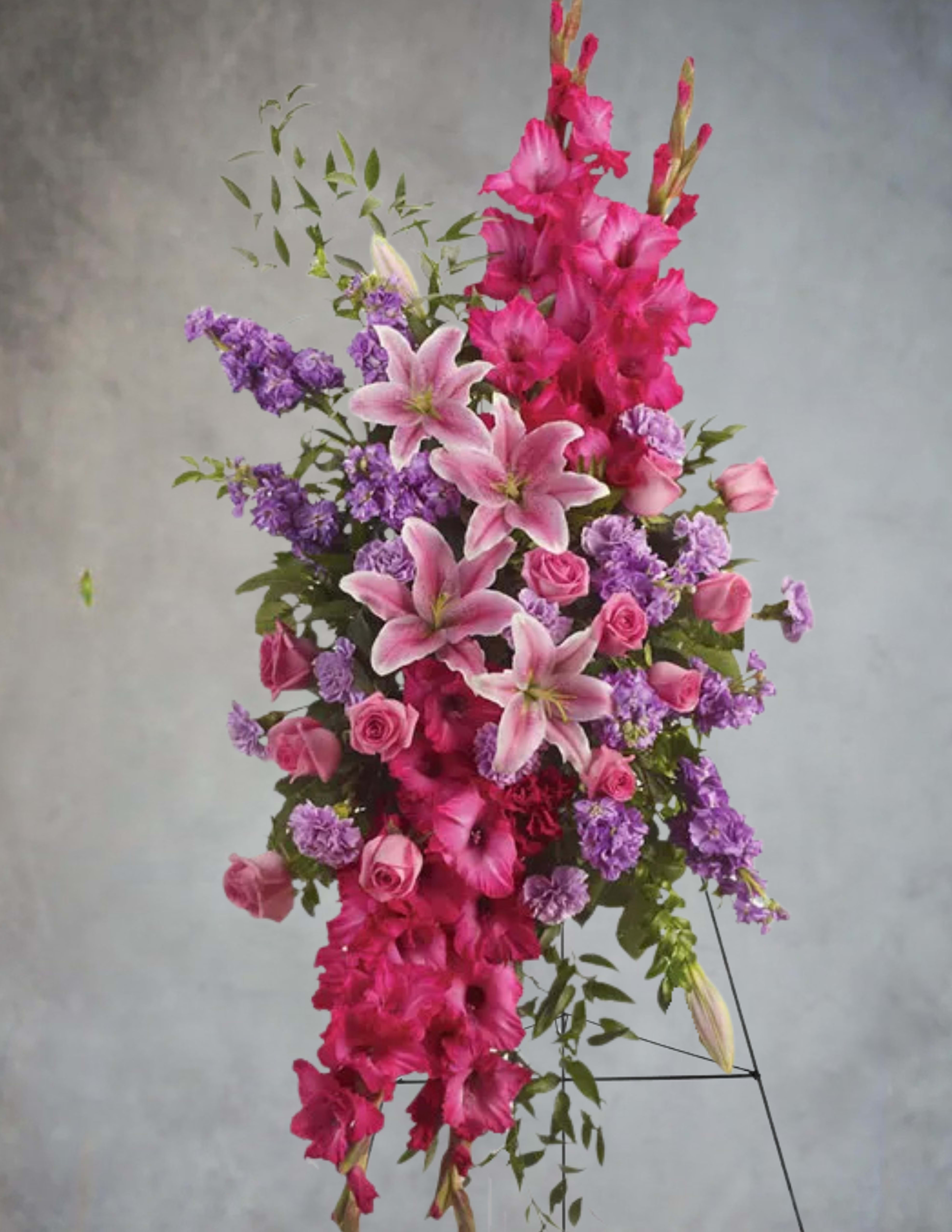 Tall arrangement of pink lilies, roses, and purple flowers