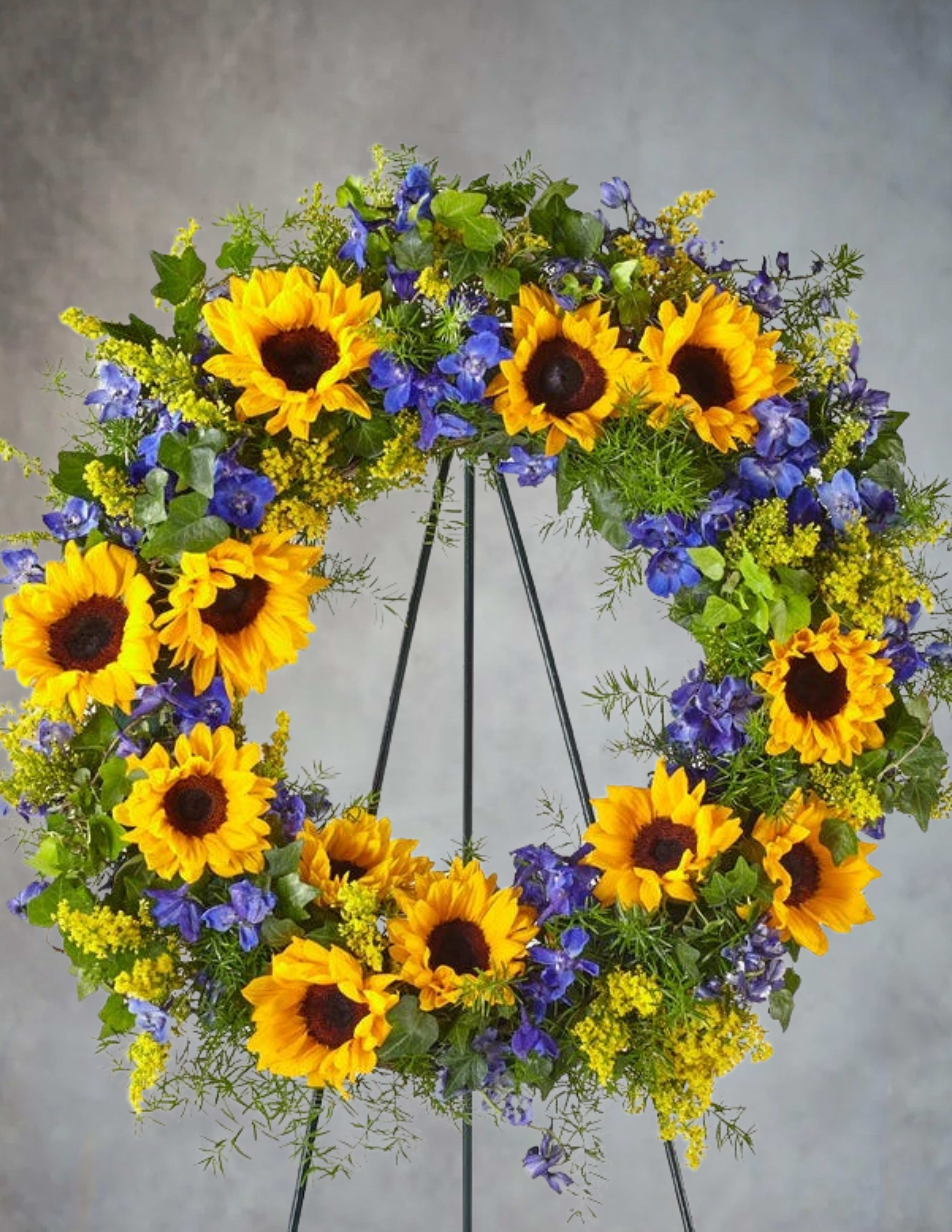 Sunflower wreath with blue flowers on a metal stand