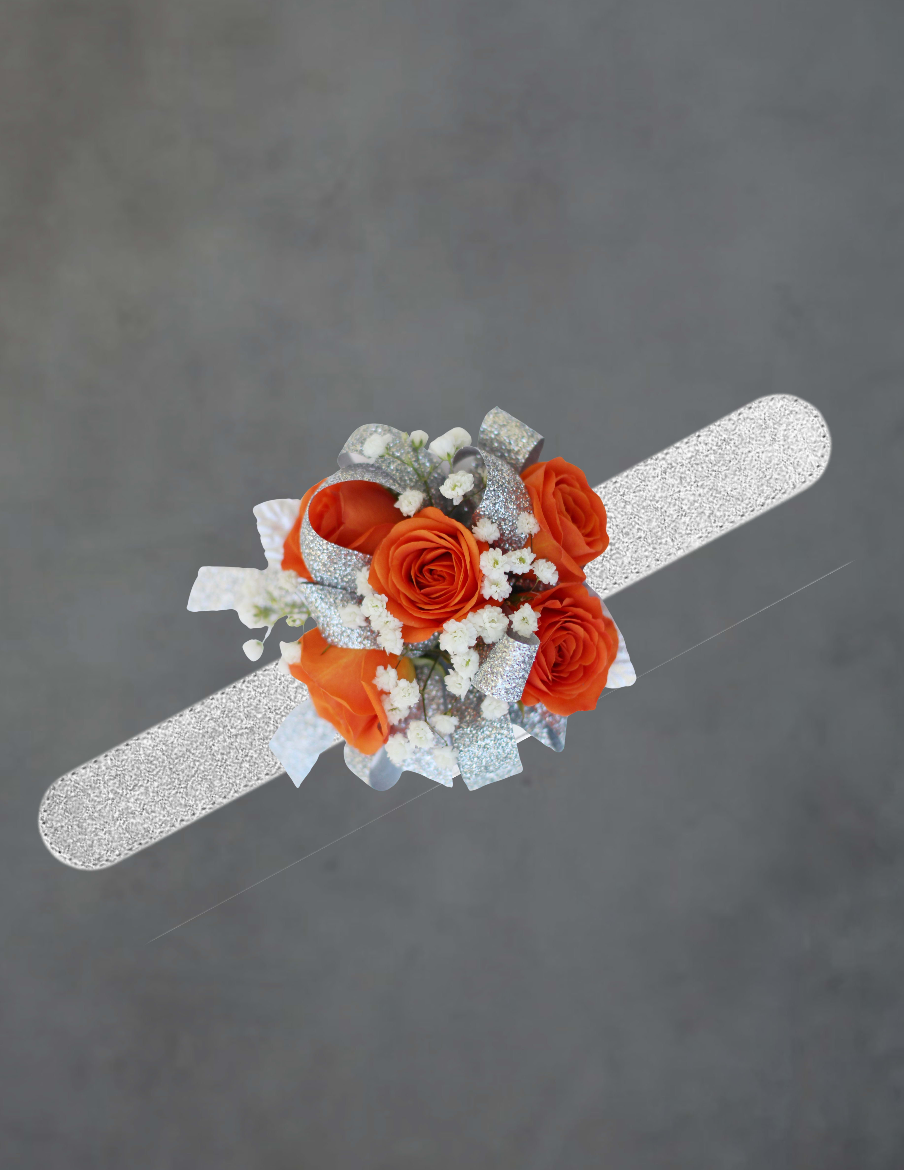 white and orange corsage - Bright clusters of bright orange roses make this wrist corsage a vivid choice for prom, homecoming, or as a wedding-related corsage that stands out on the dance floor or at the reception. The bold orange roses paired with crisp white filler flowers create a lively contrast that reads joyful and formal at the same time - the kind of corsage that will make the person you're thinking of feel celebrated and picture-ready.  Tightly clustered blooms sit on a comfortable wrist corsage band, finished with a wide silver glitter ribbon that catches light and adds a touch of sparkle to the arrangement. The mix of orange and white florals keeps the look fresh and versatile; roses are the focal flowers with small white accents layered in for texture and balance. The compact, wearable size makes it ideal for evening events where polishing details matters.  Perfect for the student heading to prom, the guest of honor at homecoming, or a bride's attendant who prefers a pop of color, this corsage pairs easily with both neutral and colorful dresses. To keep it looking its best, handle gently and avoid prolonged exposure to heat - corsages are prepared to be worn the same day for peak freshness.