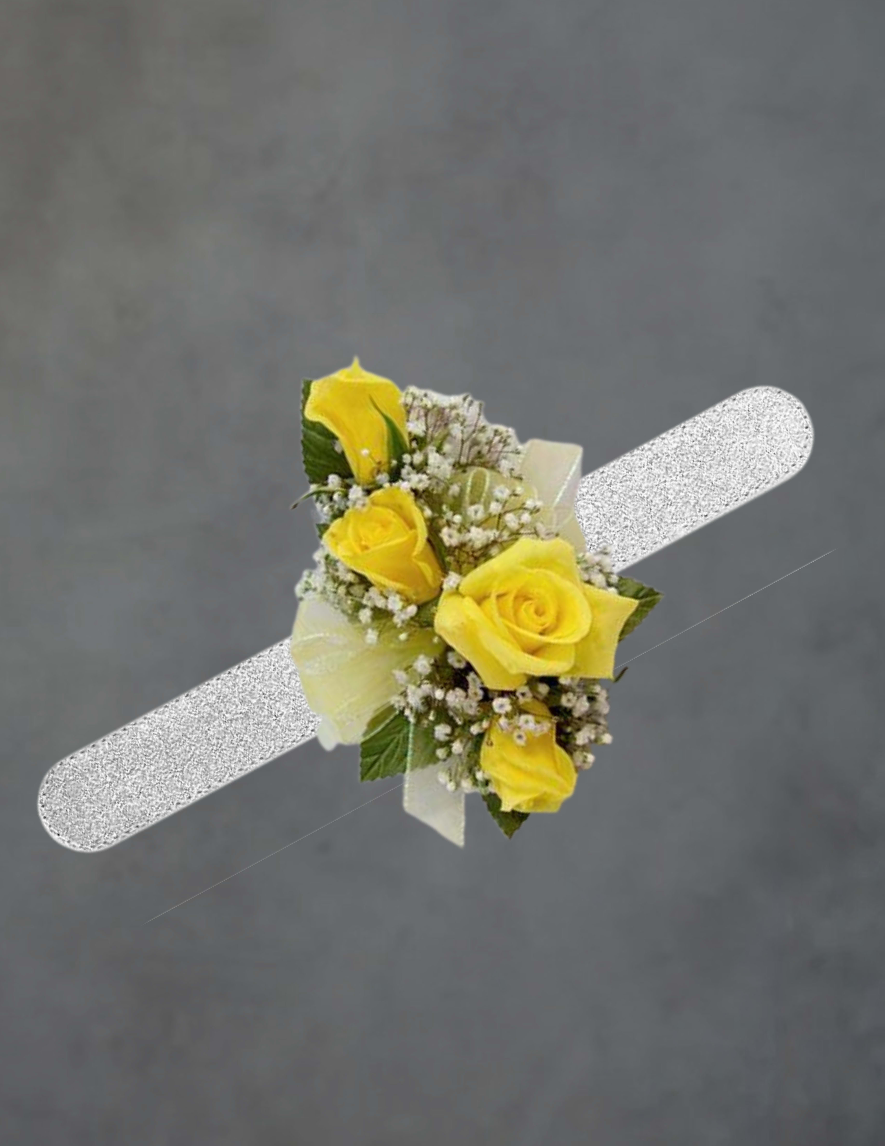yellow corsage - Sunny yellow roses take center stage in this yellow corsage, a cheerful wrist-worn arrangement perfect for prom, weddings, or any celebratory occasion where you want the person you're thinking of to feel polished and special. The compact design reads classic and fresh-an ideal choice for a mother of the bride, bridesmaid, graduate, or prom date who should stand out with warm, joyful color.  Several bright yellow roses are clustered tightly with small white filler blooms and a few green leaves for contrast, finished with a pale white ribbon beneath the blooms for a soft, formal touch. The corsage is delicate and easy to wear on the wrist, offering a clean silhouette that complements dresses or suits without overwhelming them. Order with confidence for spring and summer events; gentle misting and keeping it cool will help preserve the flowers through the day.