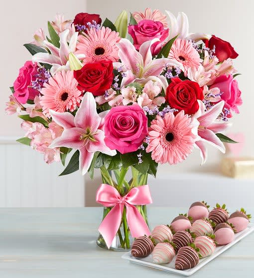 Fields of Europe Romance with Strawberries - Wow her with this lavish bouquet arranged in the romantic European tradition and strawberries dipped and decorated to perfection. Hand-arranged roses, lilies, Gerberas, alstroemeria, calcynia and salal Arrives in a stylish clear glass gathering vase accented with a satin ribbon; Our florists hand-design each arrangement, so colors, varieties, and container may vary due to local availability Lilies may arrive in bud form and will open to full beauty over the next 2-3 days Hand-dipped strawberries decorated with red and pink chocolaty swirls Available in counts of 12 strawberries Delivered fresh to their door with Same-Day Delivery.