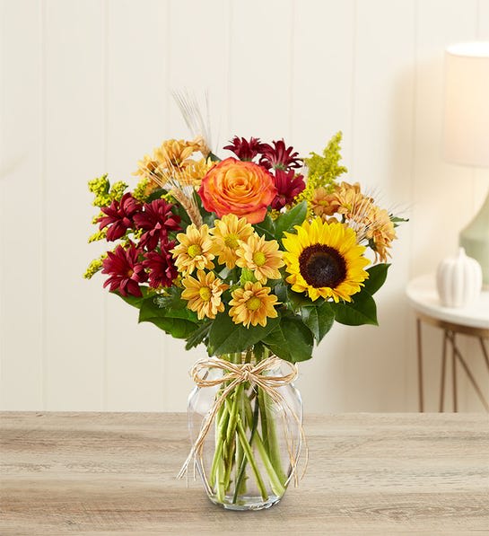 Fields of Europe for Fall - Inspired by the colorful charm of the European countryside, our best-selling autumn bouquet is gathered with fresh-picked flowers, revealing the rustic beauty of nature. Shades of golden yellow, rich red and pops of orange create a timeless gift for someone special to enjoy.  All-around arrangement with autumn-colored roses, sunflowers, orange Asiatic lilies, red and autumn-colored daisy poms; accented with wheat, solidago and assorted greenery Artistically designed in a clear glass vase accented with raffia; measures 8"H Large arrangement measures approximately 17"H x 13"W Medium arrangement measures approximately 16"H x 12"W Small arrangement does not include Asiatic lilies; measures approximately 15"H x 11"W Our florists hand-design each arrangement, so colors, varieties, and container may vary due to local availabilityTo ensure lasting beauty, lilies may arrive in bud form and will fully bloom over the next few days Sunflowers may have light or dark centers, based on local availability