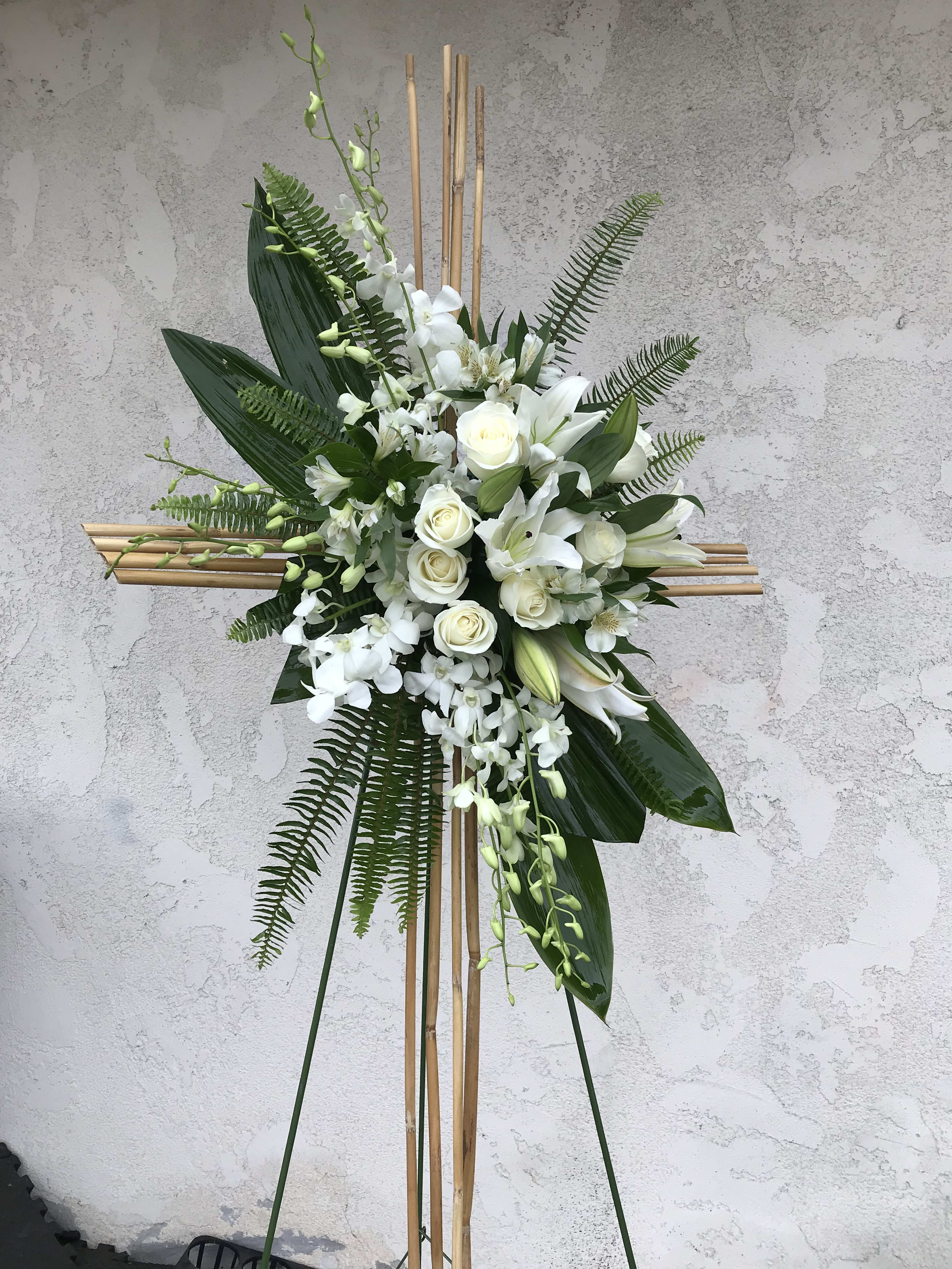 White floral standing spray on a bamboo cross frame