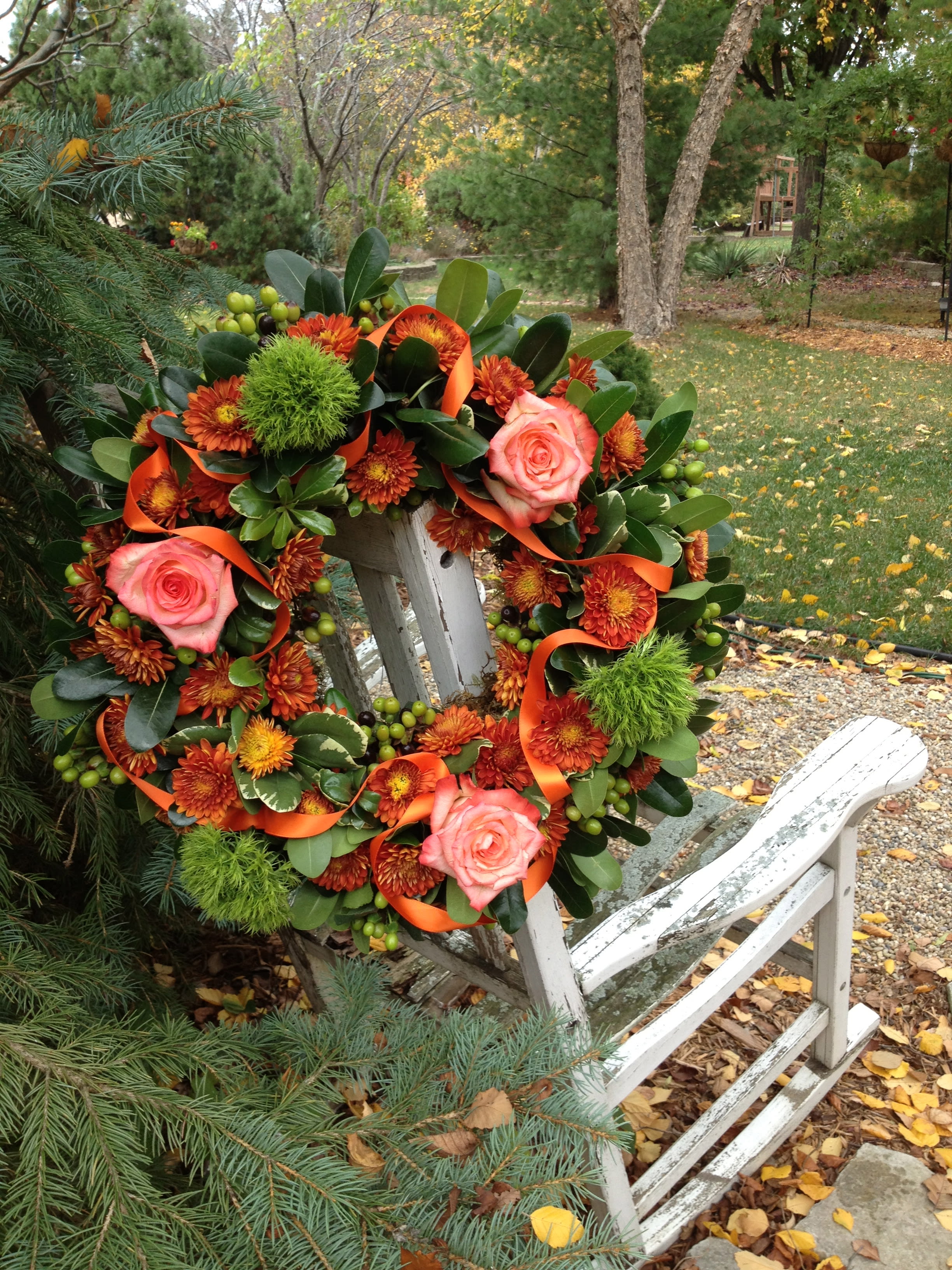 Autumn wreath with pink roses and orange flowers on a white chair