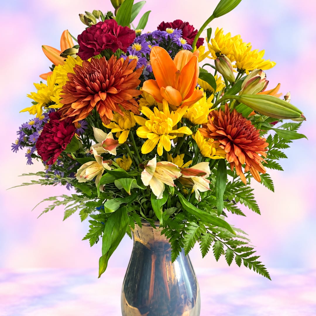 Mixed bouquet of orange, yellow, purple, and red flowers in a glass vase