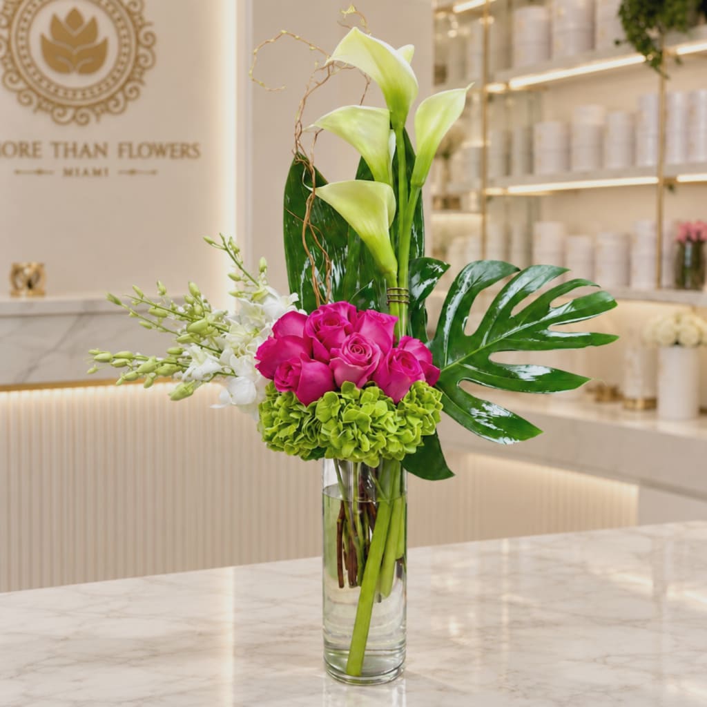 Pink roses and green calla lilies in a clear glass vase