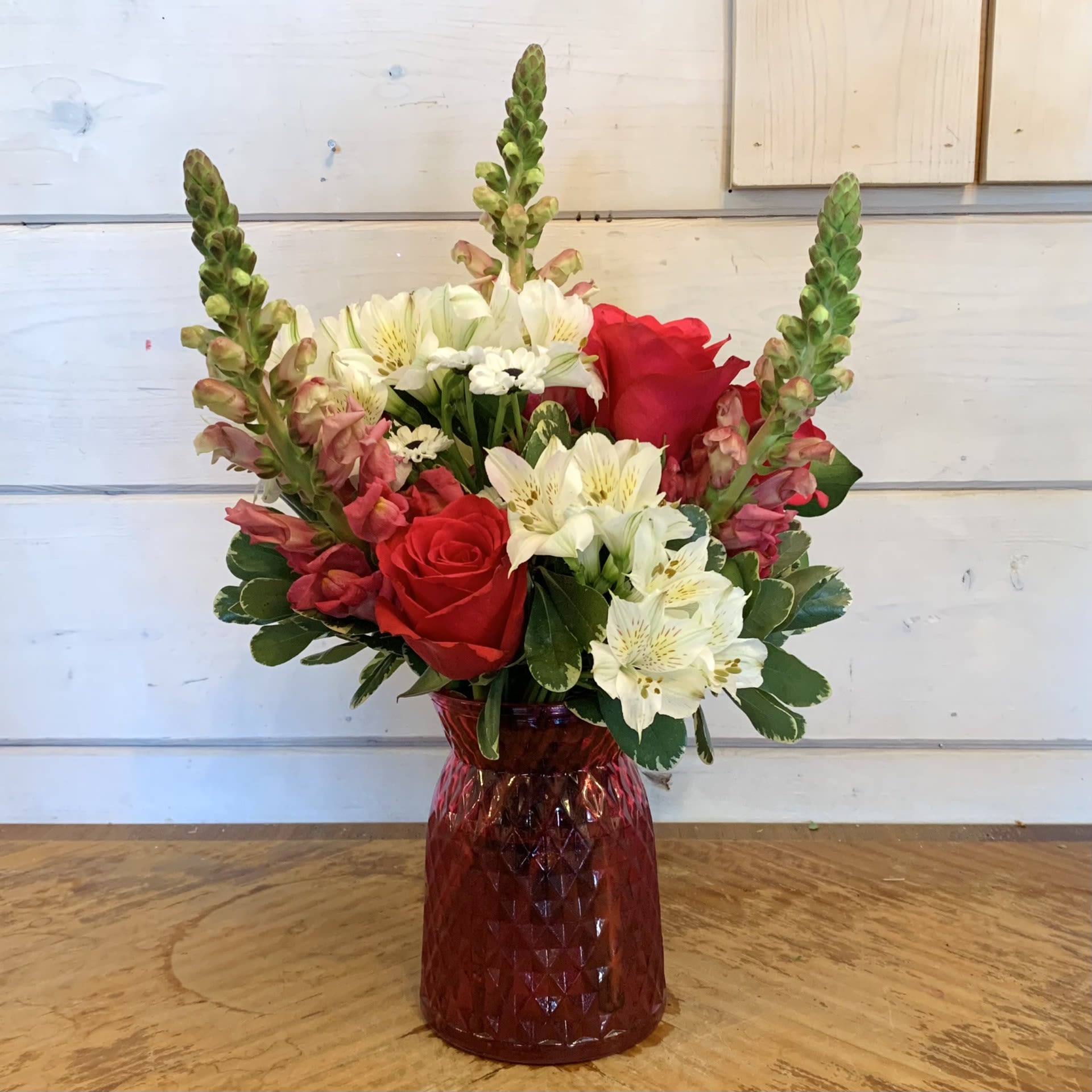 Red roses and white alstroemeria in a red glass vase